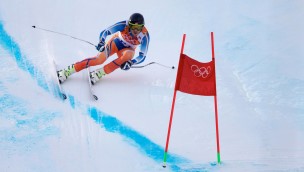 Alpine skiers in the slope at high speed getting ready to pass a gate.