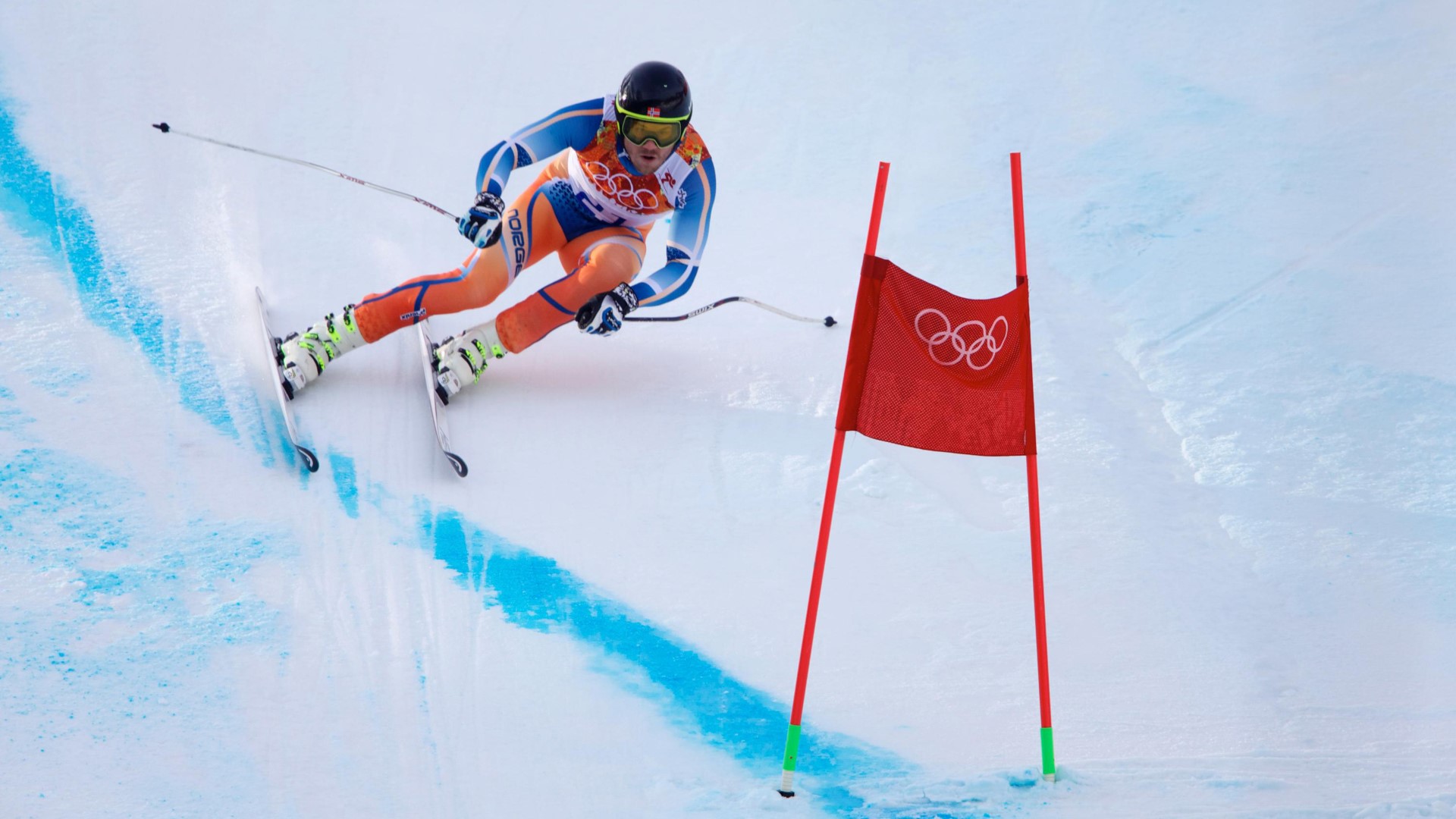 Alpine skiers in the slope at high speed getting ready to pass a gate.