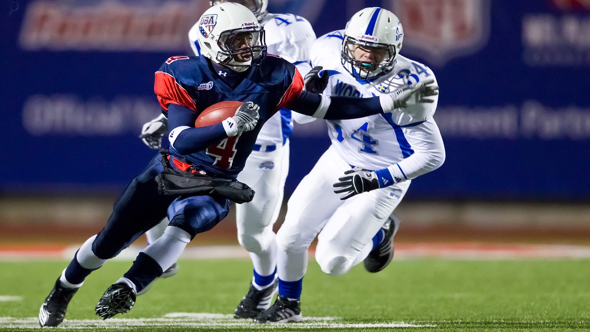 Two athletes in a match, one running with the ball the other running after him.