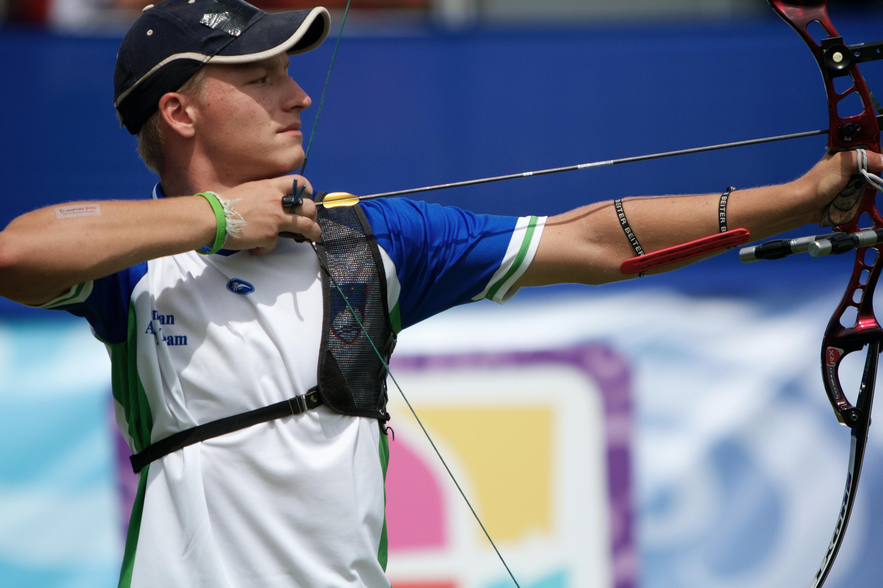 Archer getting ready to shot, arrow drawn backwards with his right hand, holding the bow with the left arm.
