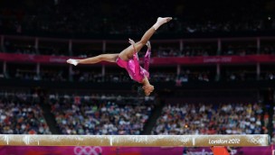 Gymnast in an Olympic competiton upside down in the air doing a split.
