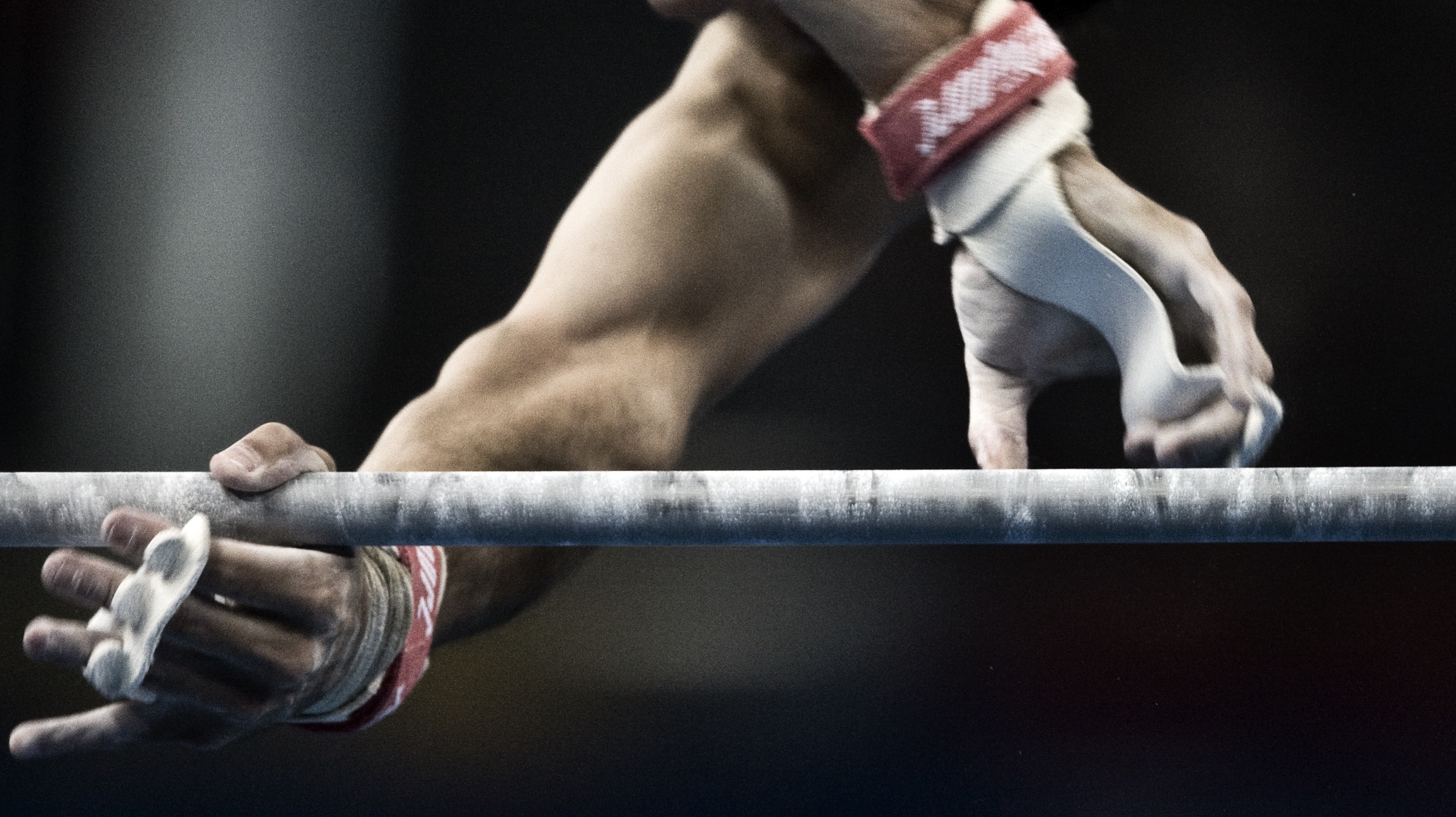 Arms and hands, close up, of an athlete holding onto a gymnastic bar.