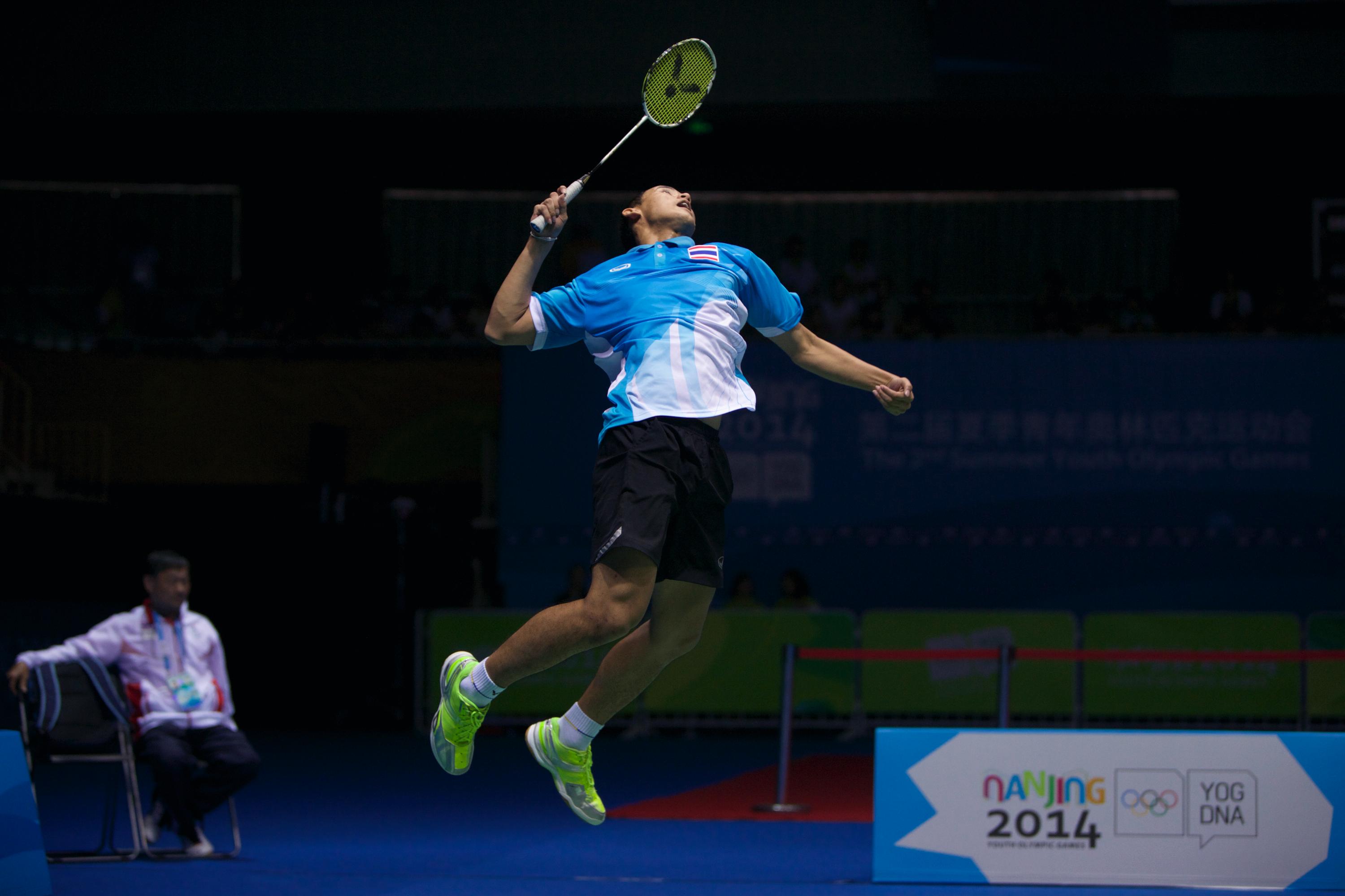 Player in a match ready to hit the light feather-ball with his racket, athlete is high up in the air.