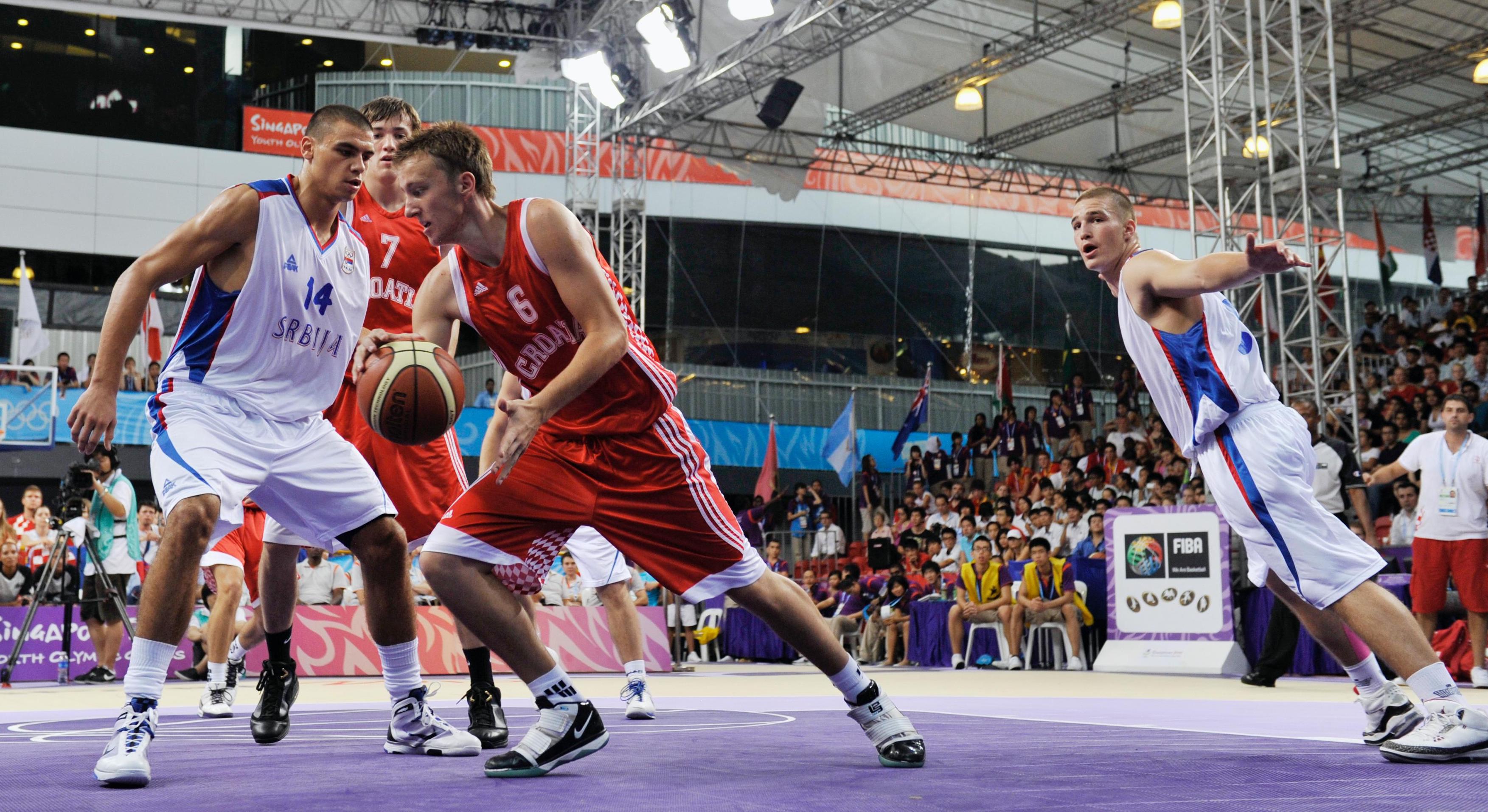 Basketball match, several players on the field, one with the ball dribling.