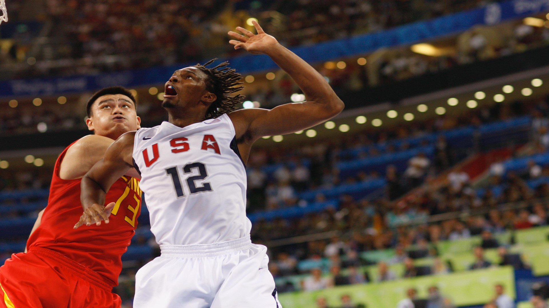 Two basketball players in a match, both jumping up close to each other with eyes looking up.