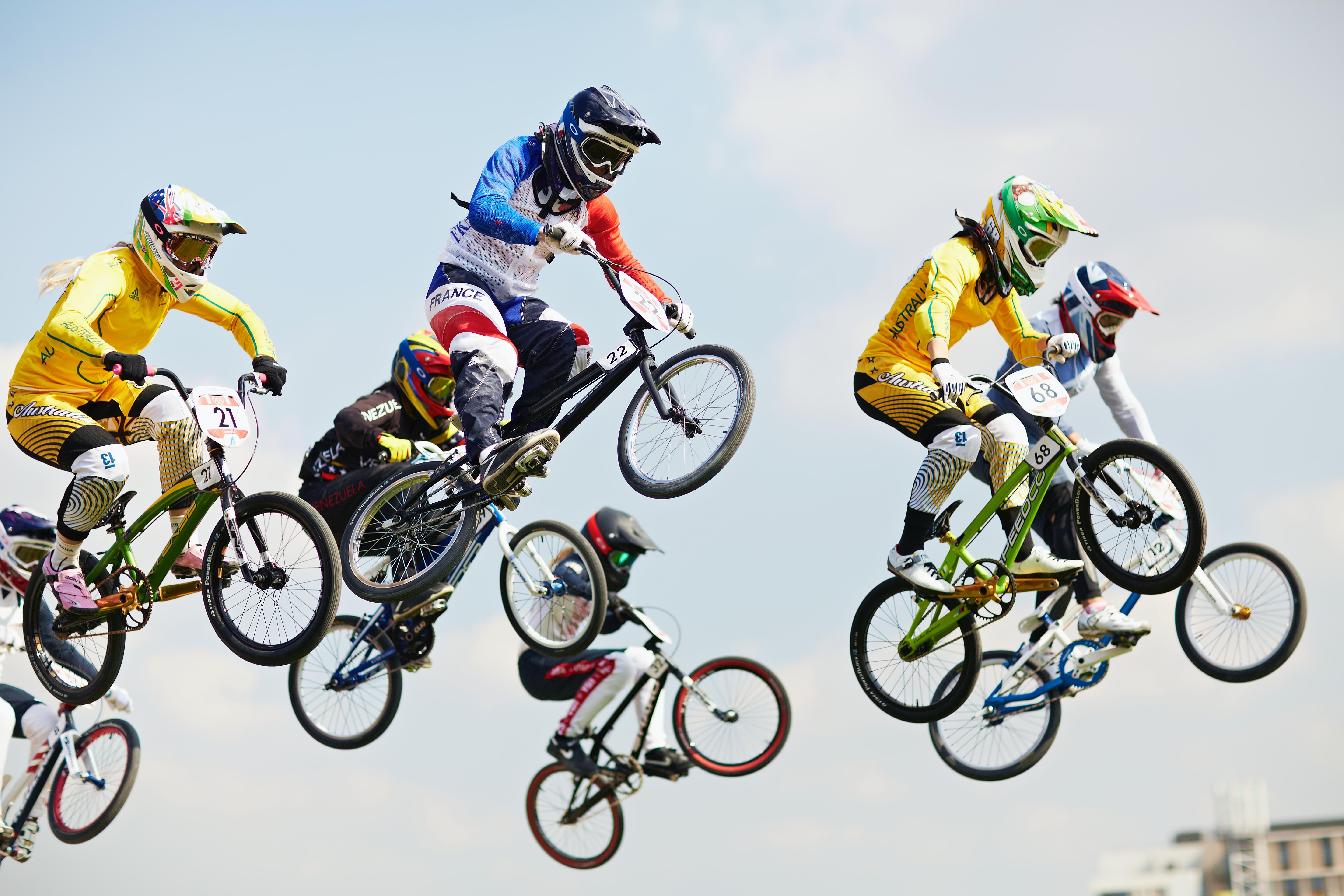 Several BMX cyclists high in the air during a competition.