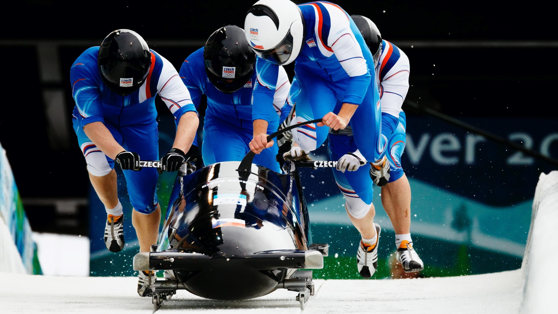 Start of the race, 4 athletes running while holding on to the bobsleigh.