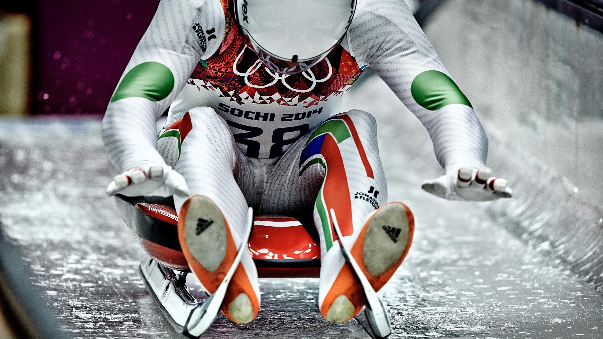 Athlete sitting on the luge pushing with both his hands on the ice to get speed.