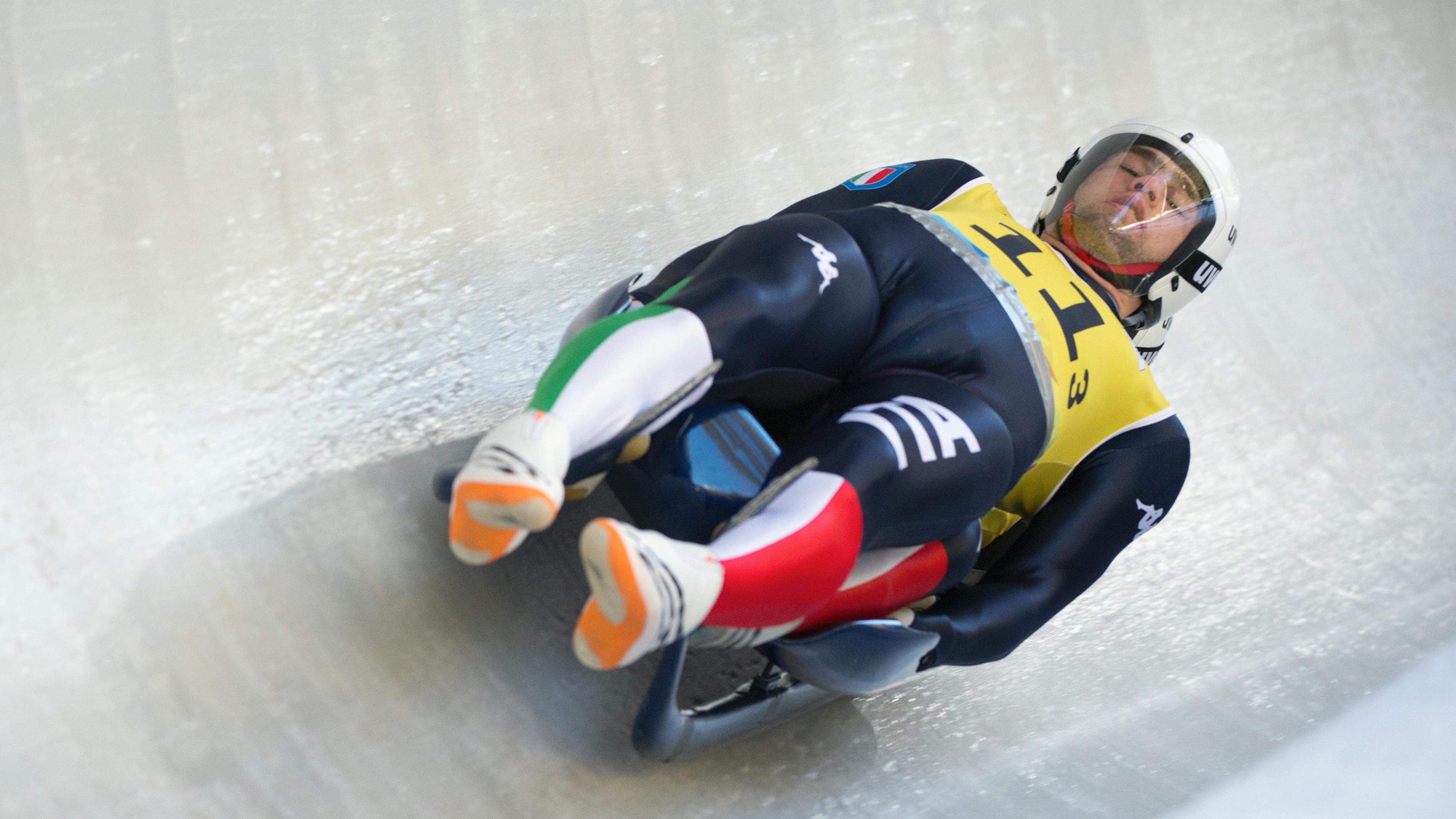 Luge athlete in the slope, lying on his back, straight, with his eyes closed.