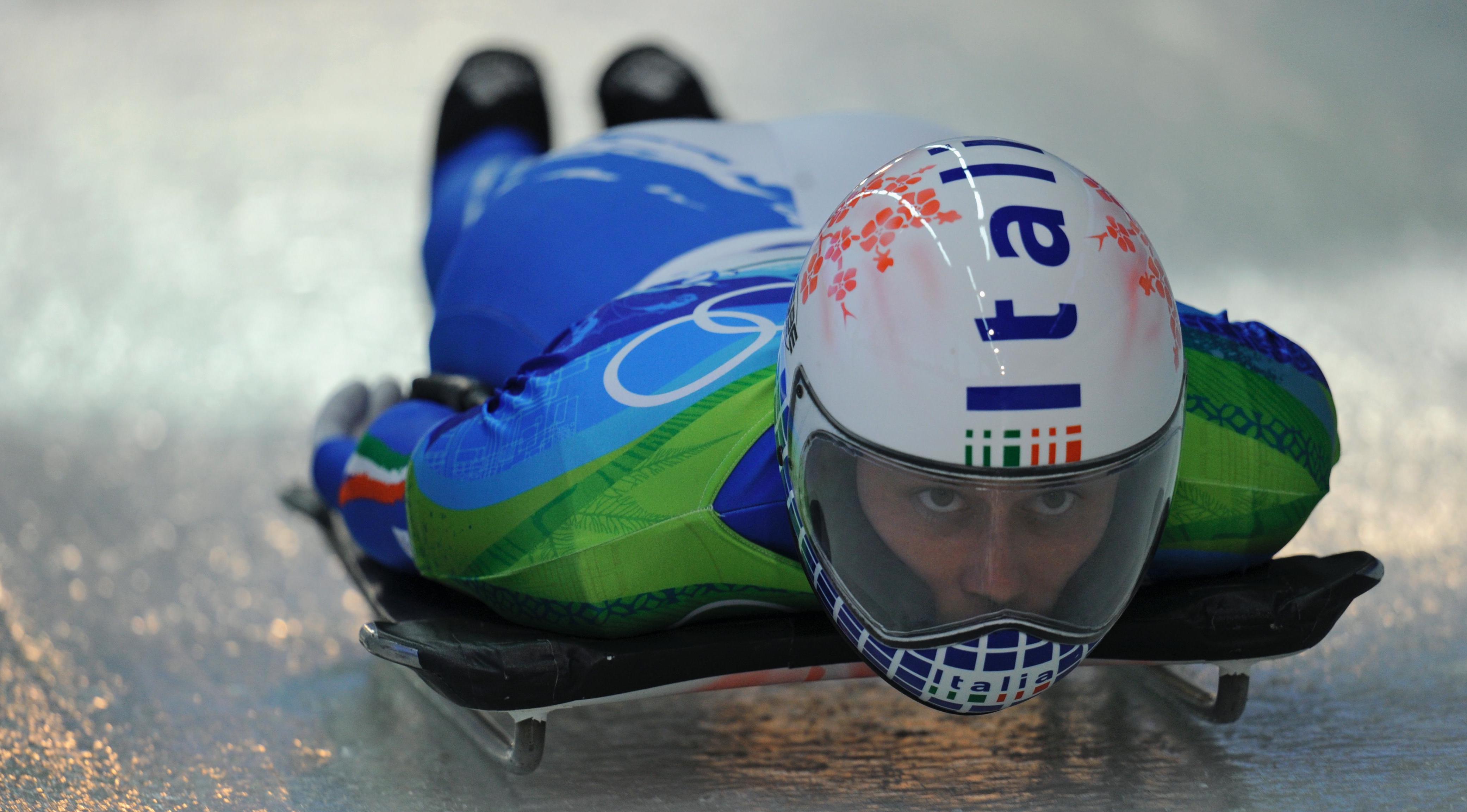 Athlete lying on the skeleton, arms to the side, helmet on, eyes forward.