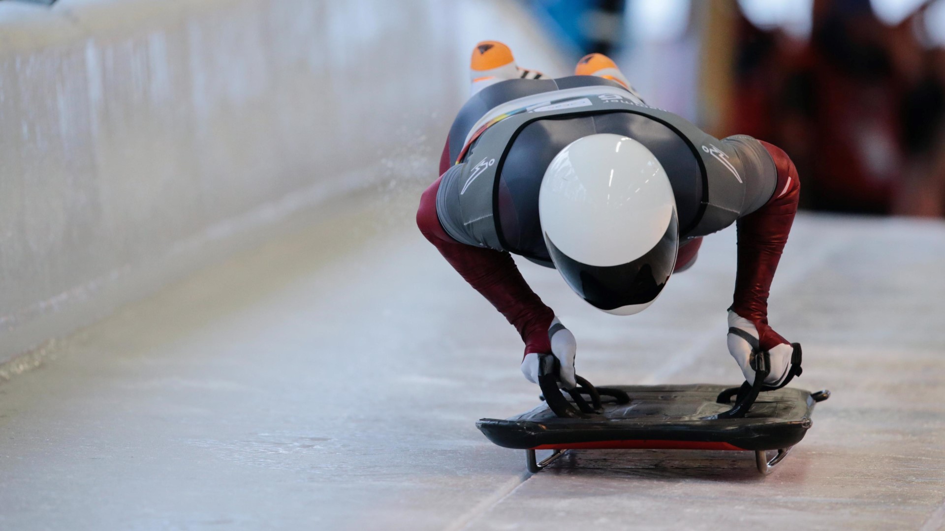 Athlete jumping forward, in the air, while holding onto the skeleton, starting a race.
