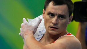 Athlete with a ice-pack on his shoulder, using his left hand to hold it in place.
