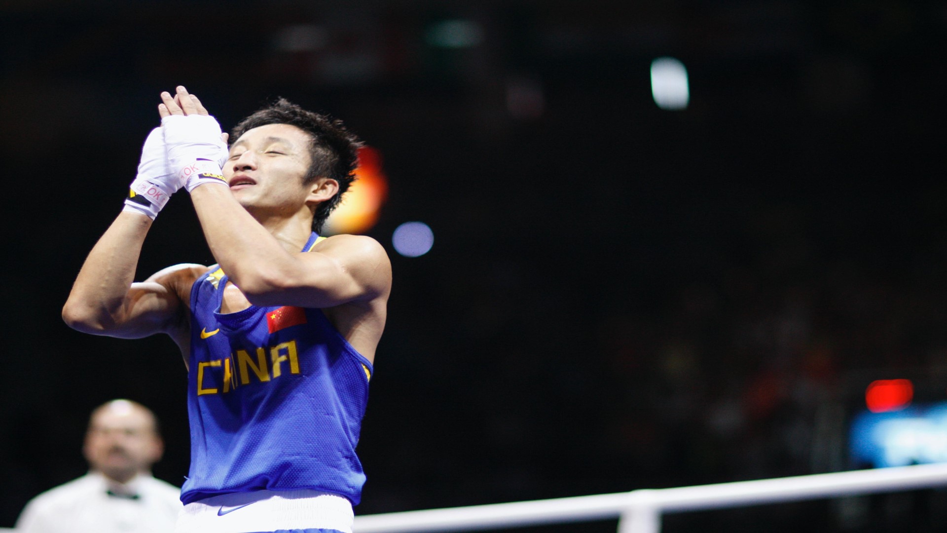 Boxer in the ring, his hand folded in front of his face with his eyes closed.