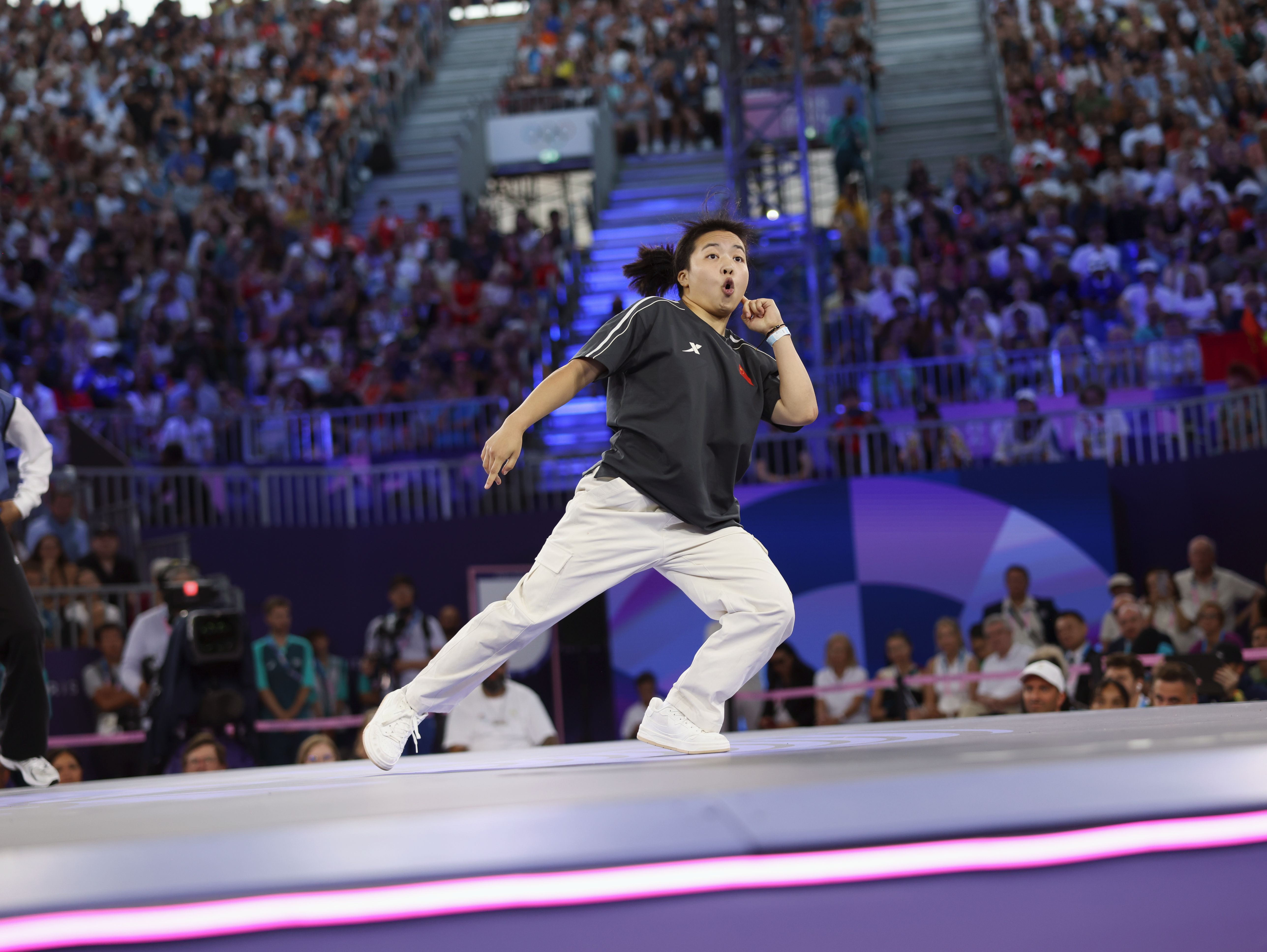 Athlete in an Olympic competition, standing a little bendt to the side, left hand to the side of the face, mouth a little open.