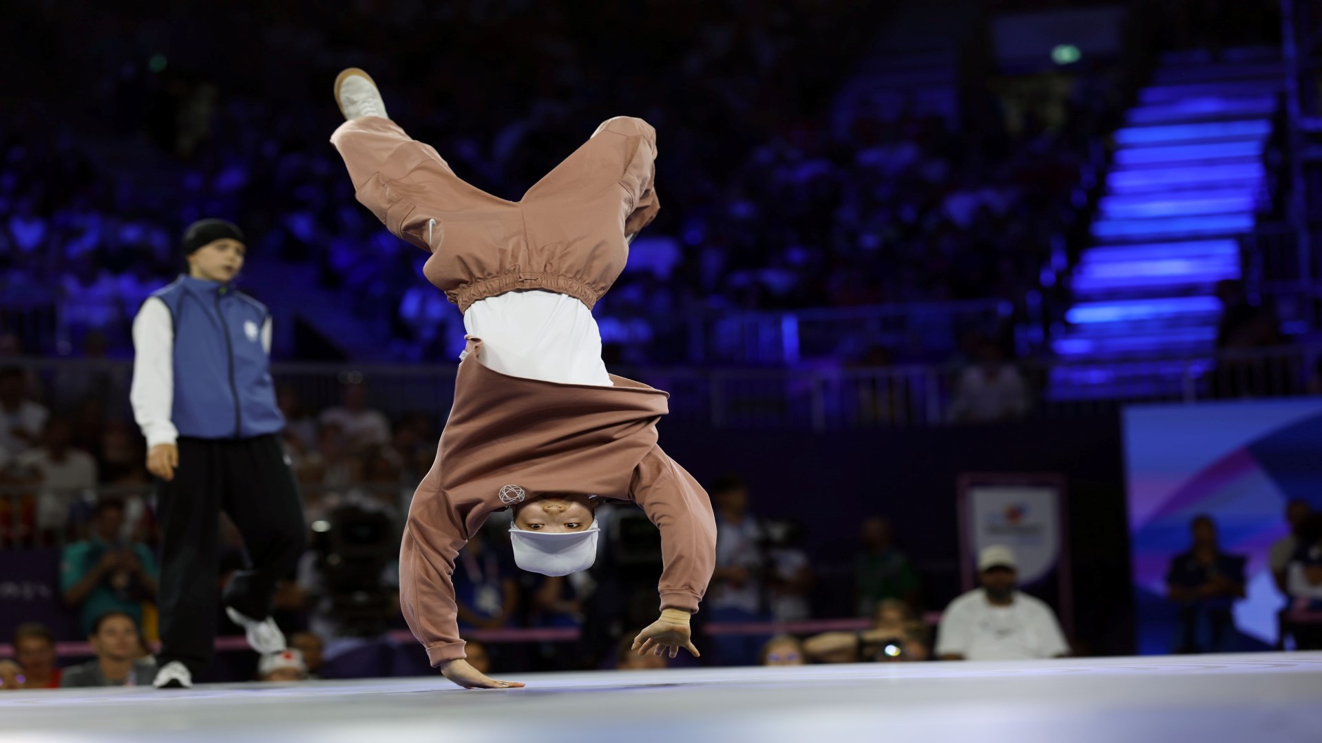 Breaker in a competition, inside, standing on her hands, up-side-down.