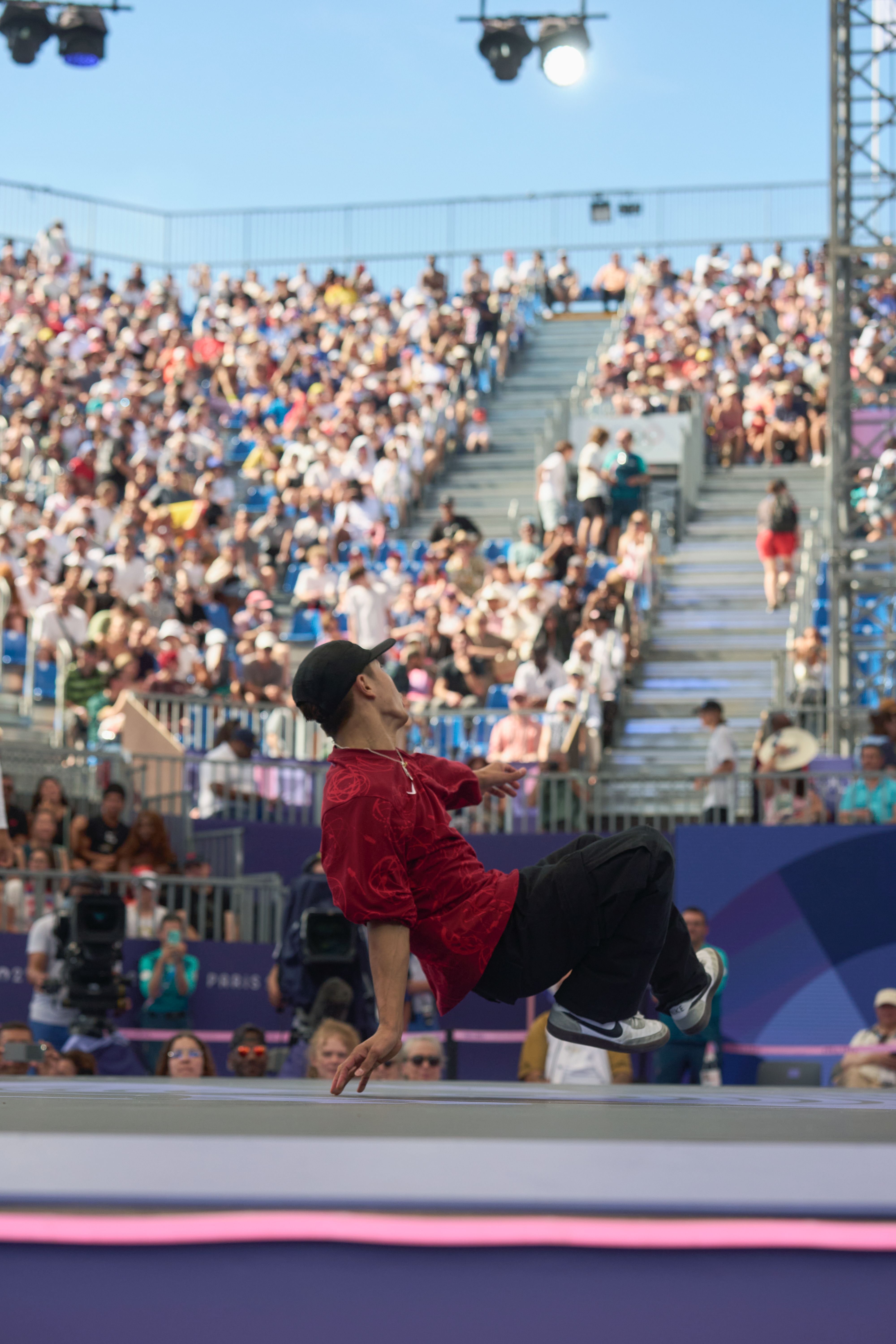 Breaker in a competition on stage, on the stage, crowd and stadium in the background.