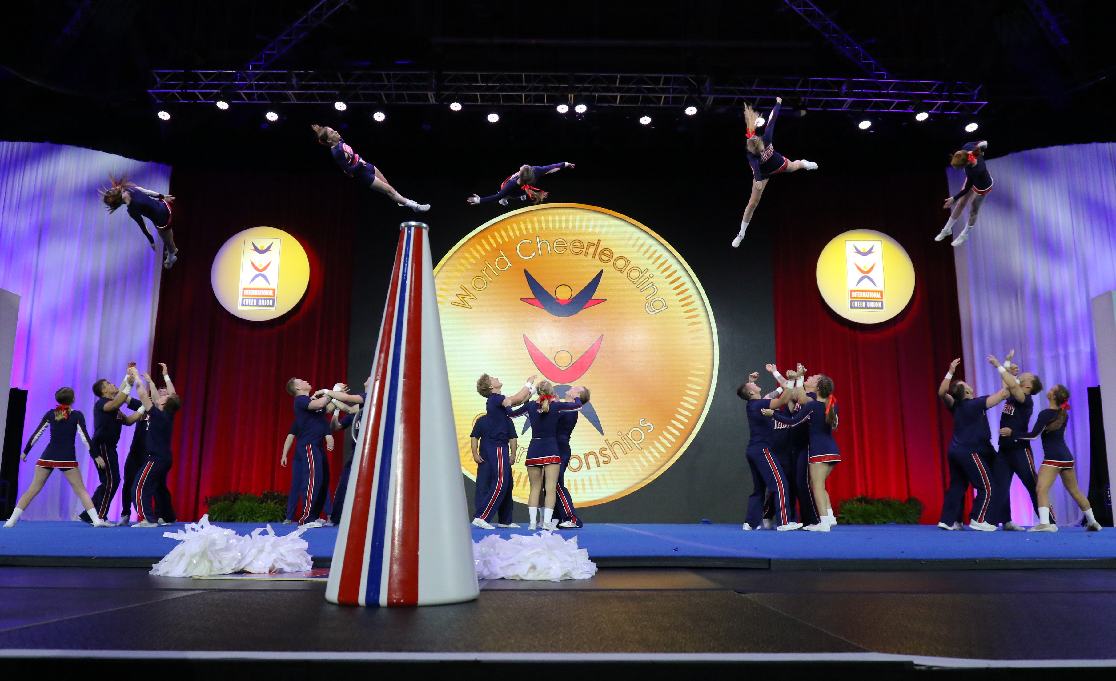 Cheerleading competition with several athlete, that have thrown several athletes in the air and are ready to catch them again.