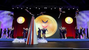 Cheerleading competition with several athlete, that have thrown several athletes in the air and are ready to catch them again.