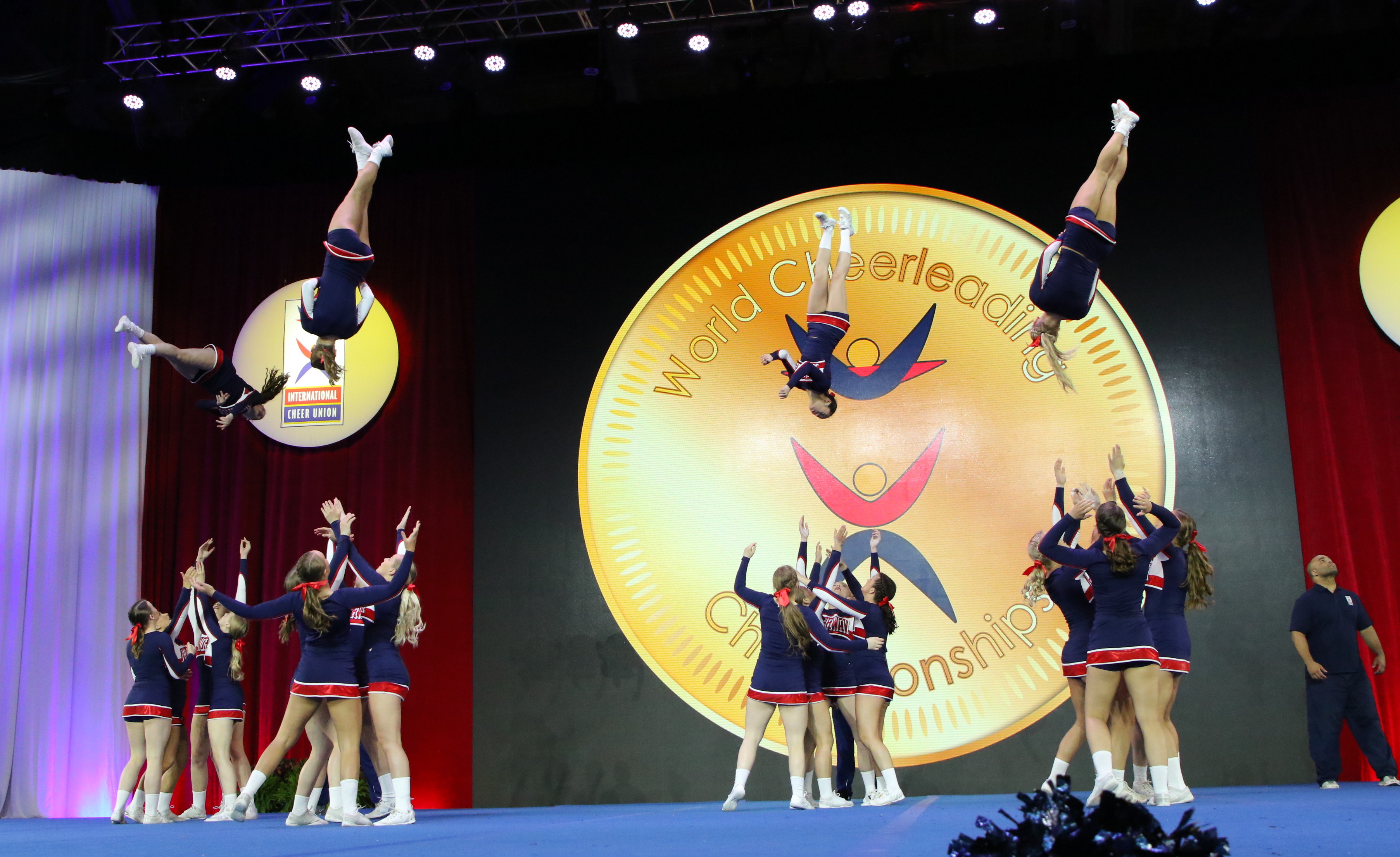 Several cheerleaders throwing other athletes in the air during a competition.