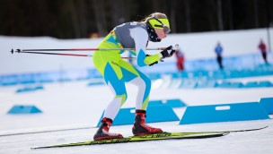 Skier on the snow in a race, slightly in a hockey position, looking forward.