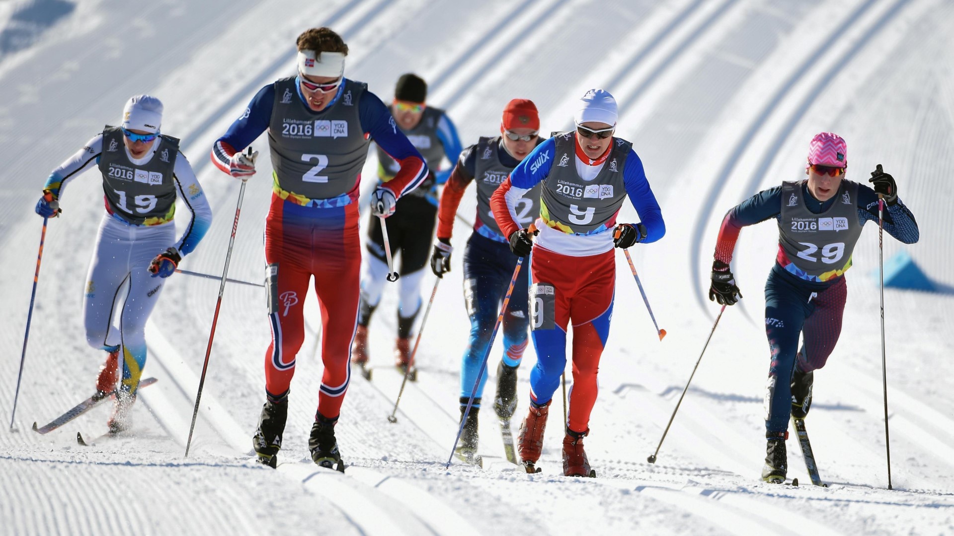 Cross country skiers seen from the front in a competition up a small hill.