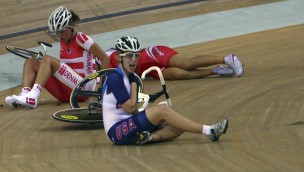 Three cyclist on an indoor cycling track, alle have fallen down, one of the athletes are holding the right hand on her left collarbone. 