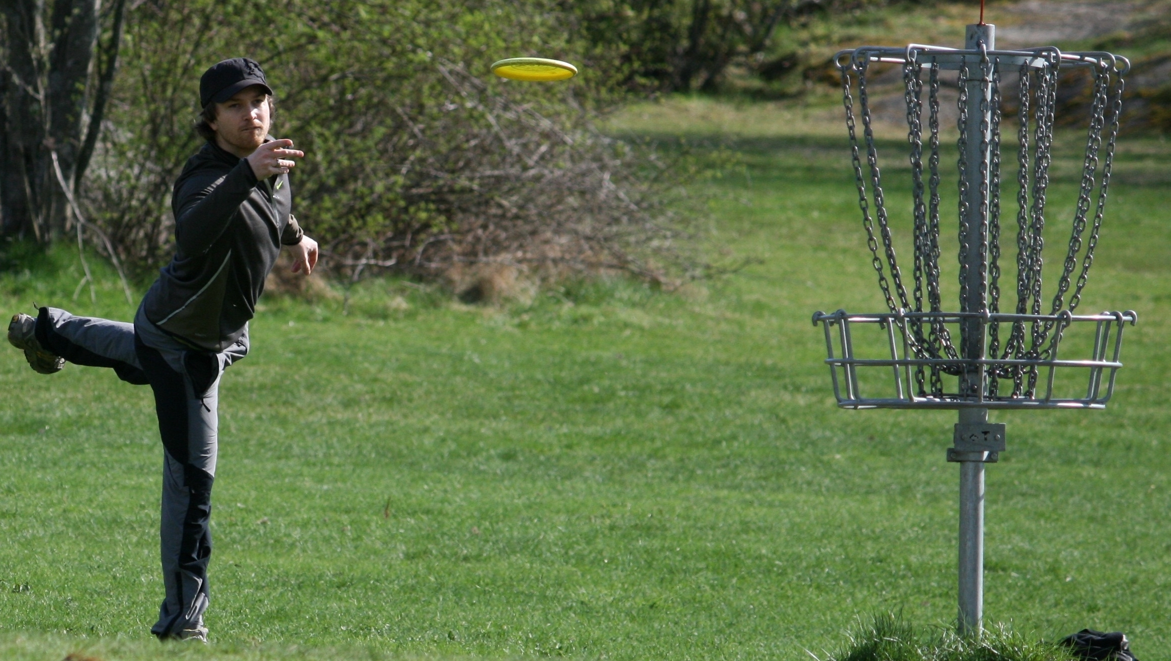 Athlete throwing a disc into the disc-basket.