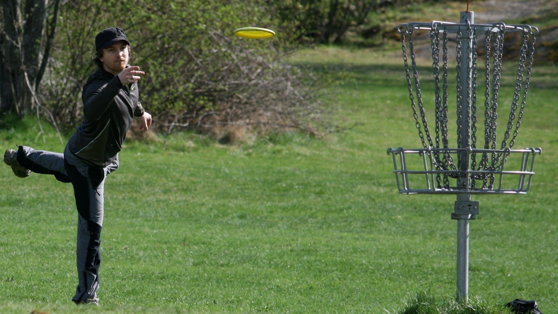 Athlete throwing a disc into the disc-basket.