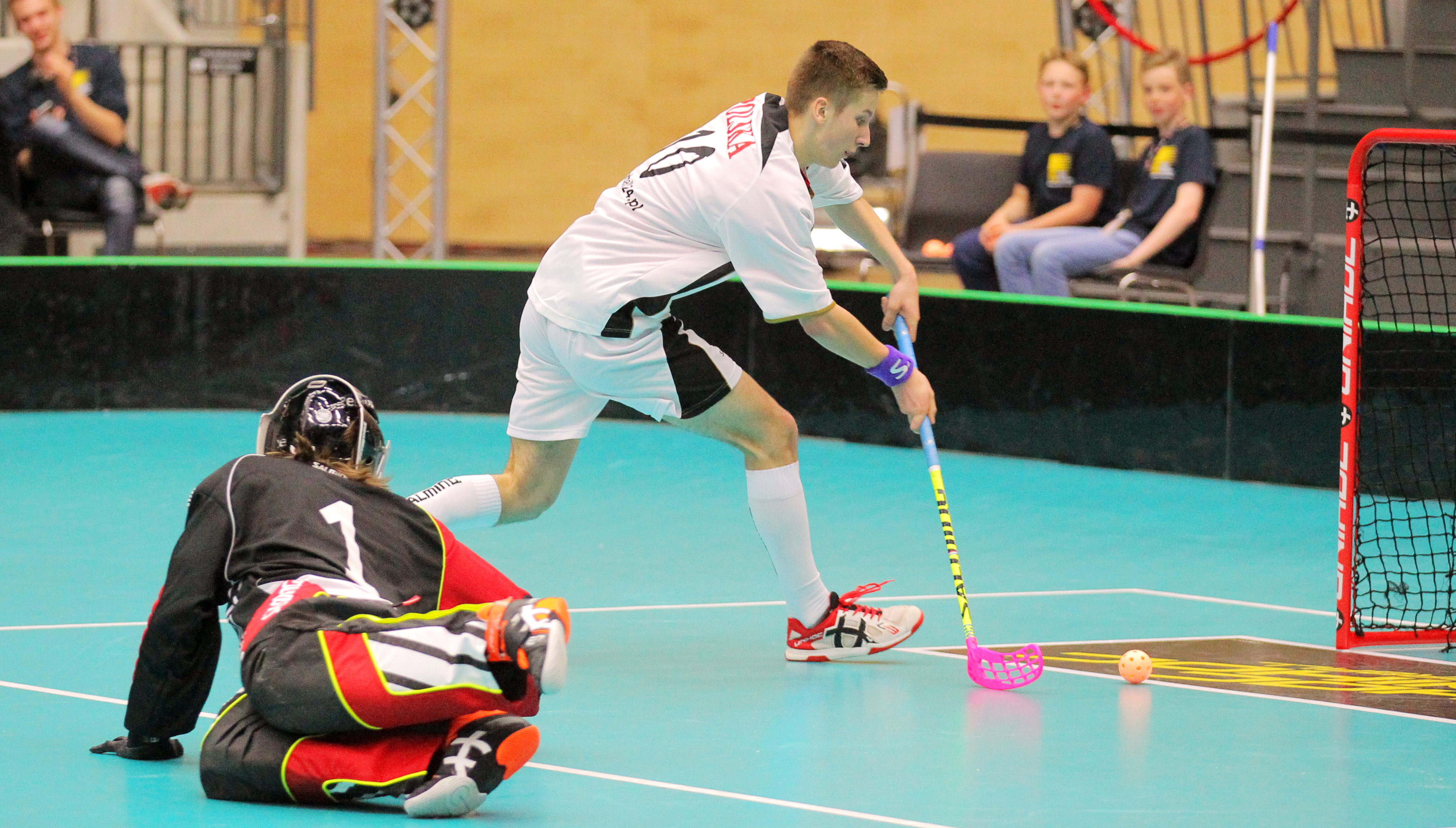 Athlete in a floorball match has just passed the goalkeeper and is to hit the ball into the open goal.