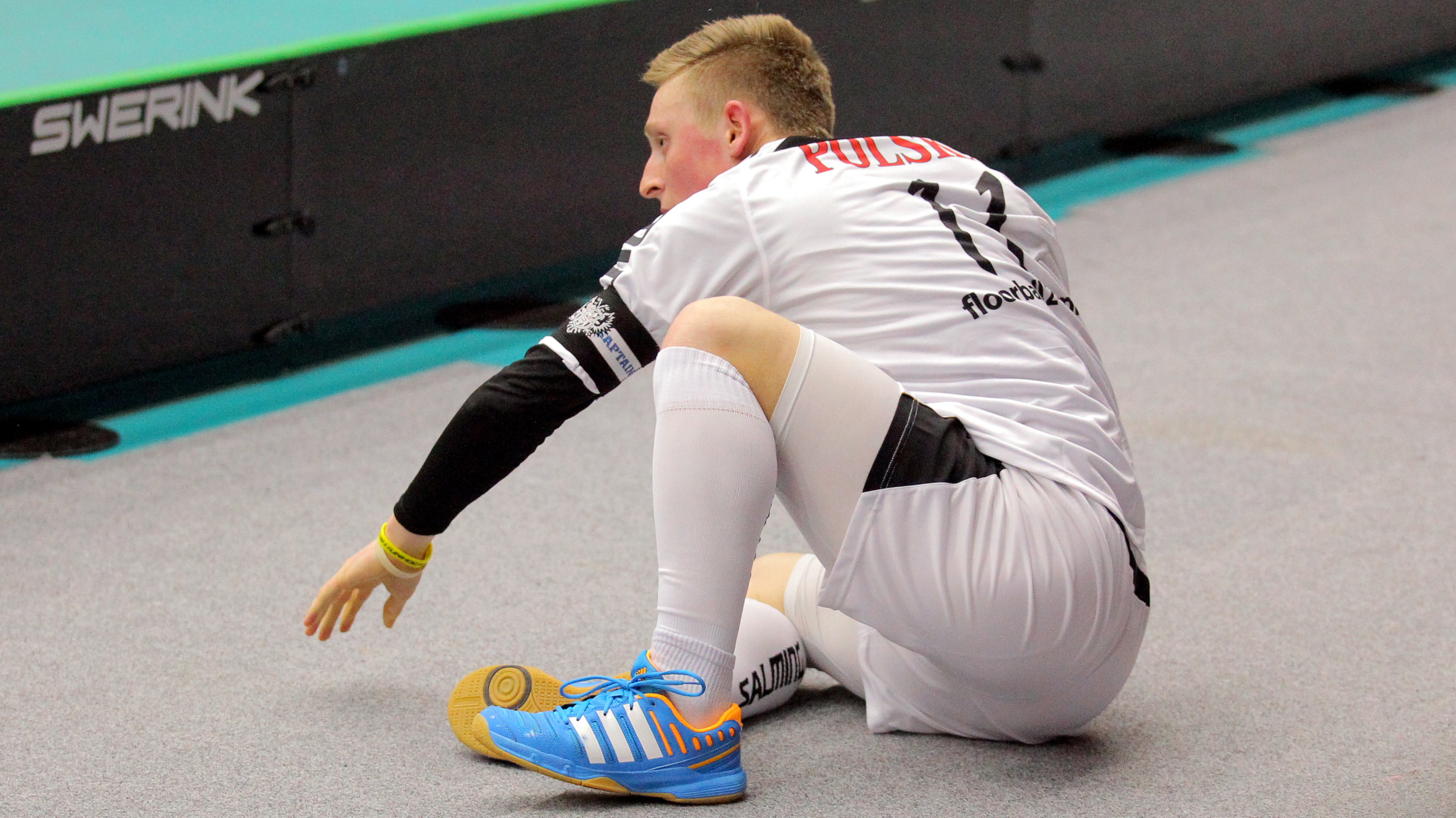 Player on the side of the court, halfway sitting down, on his way to stand up.