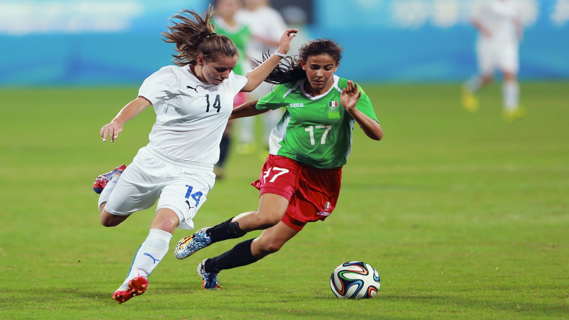 Two footballers on the field running after the ball.