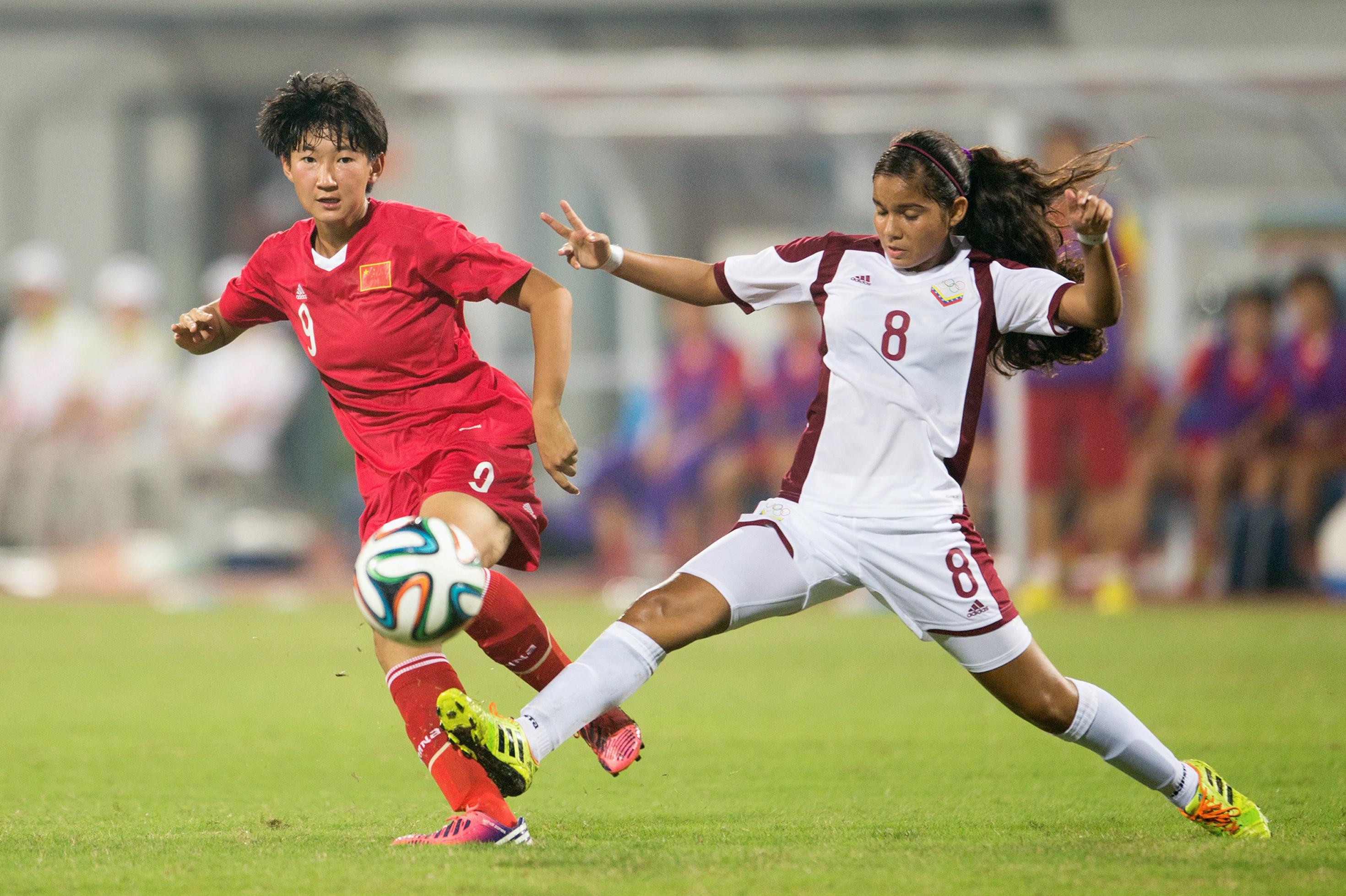 Two football players on the field, where one is trying to tackle the other, but the ball is already passed.