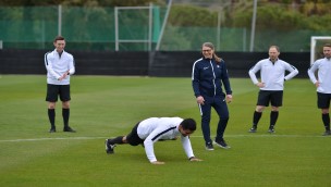 Referees on training on the field, one doing a push-up, physician observing with other referees.