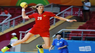 Handballplayer jumping with the ball in her hand.