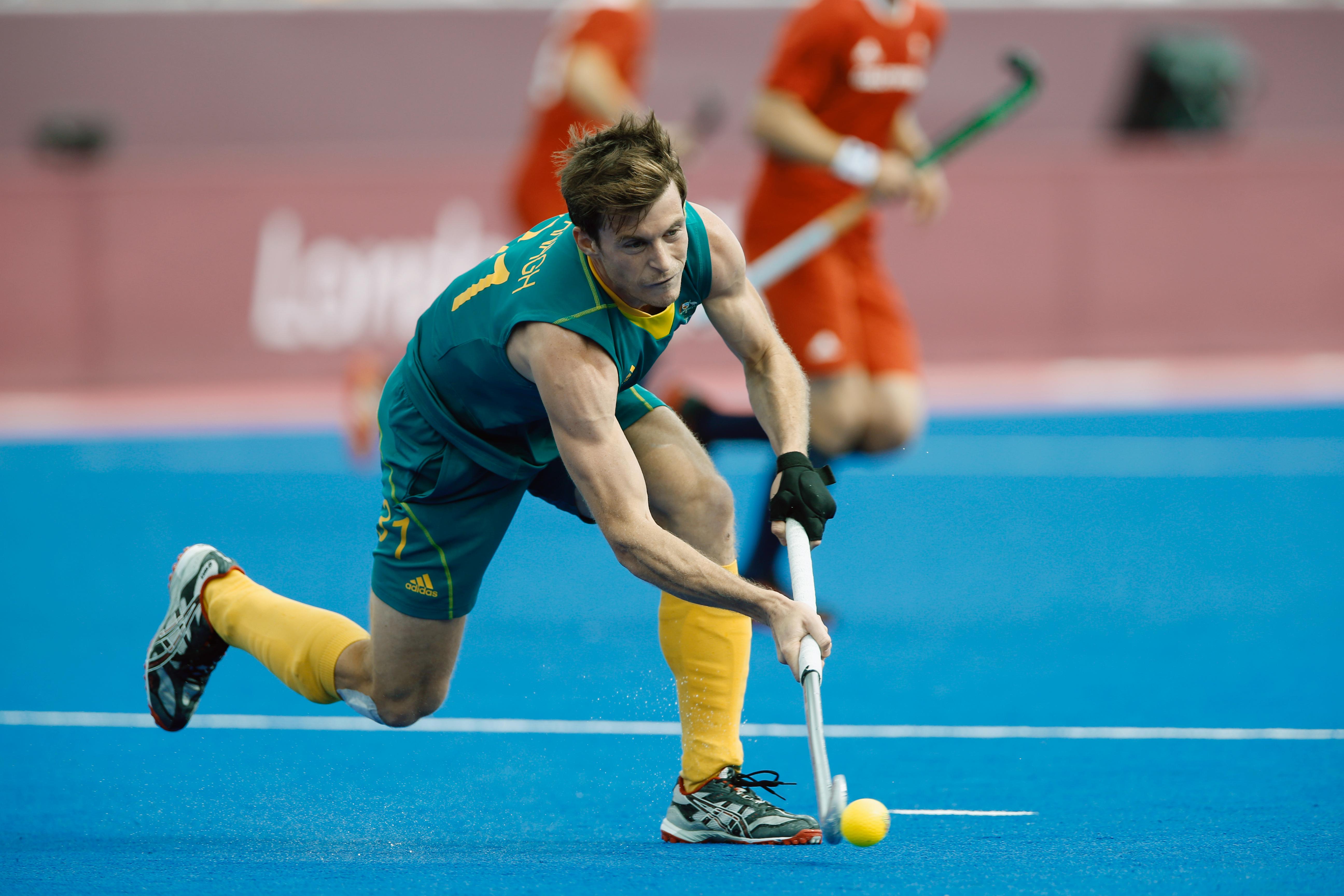 Athlete on the field moving forward, slightly bendt, while moving the ball forward with his hockeystick.