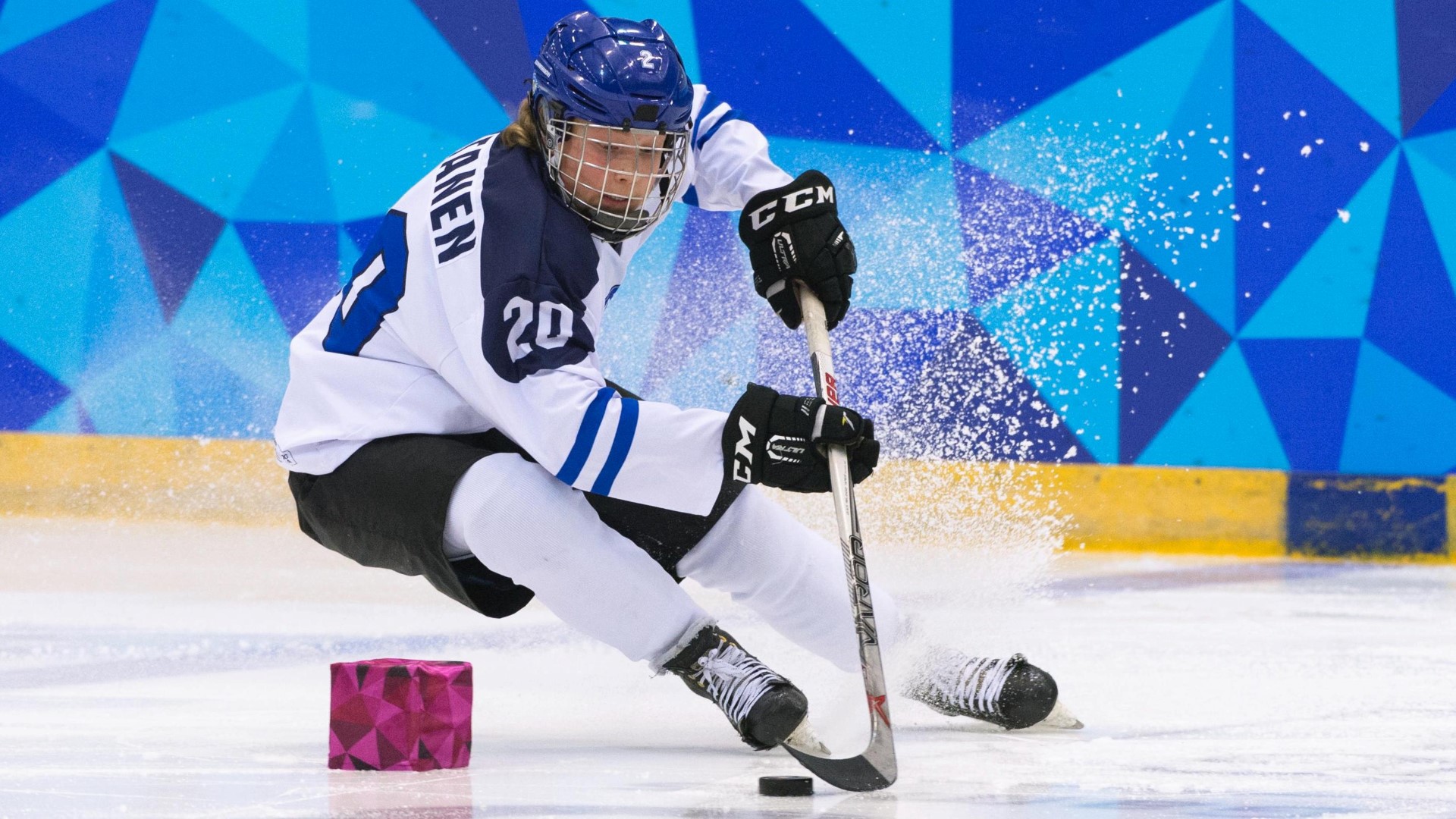 Ice hockey player on the ice making a turn while in control of the puck.
