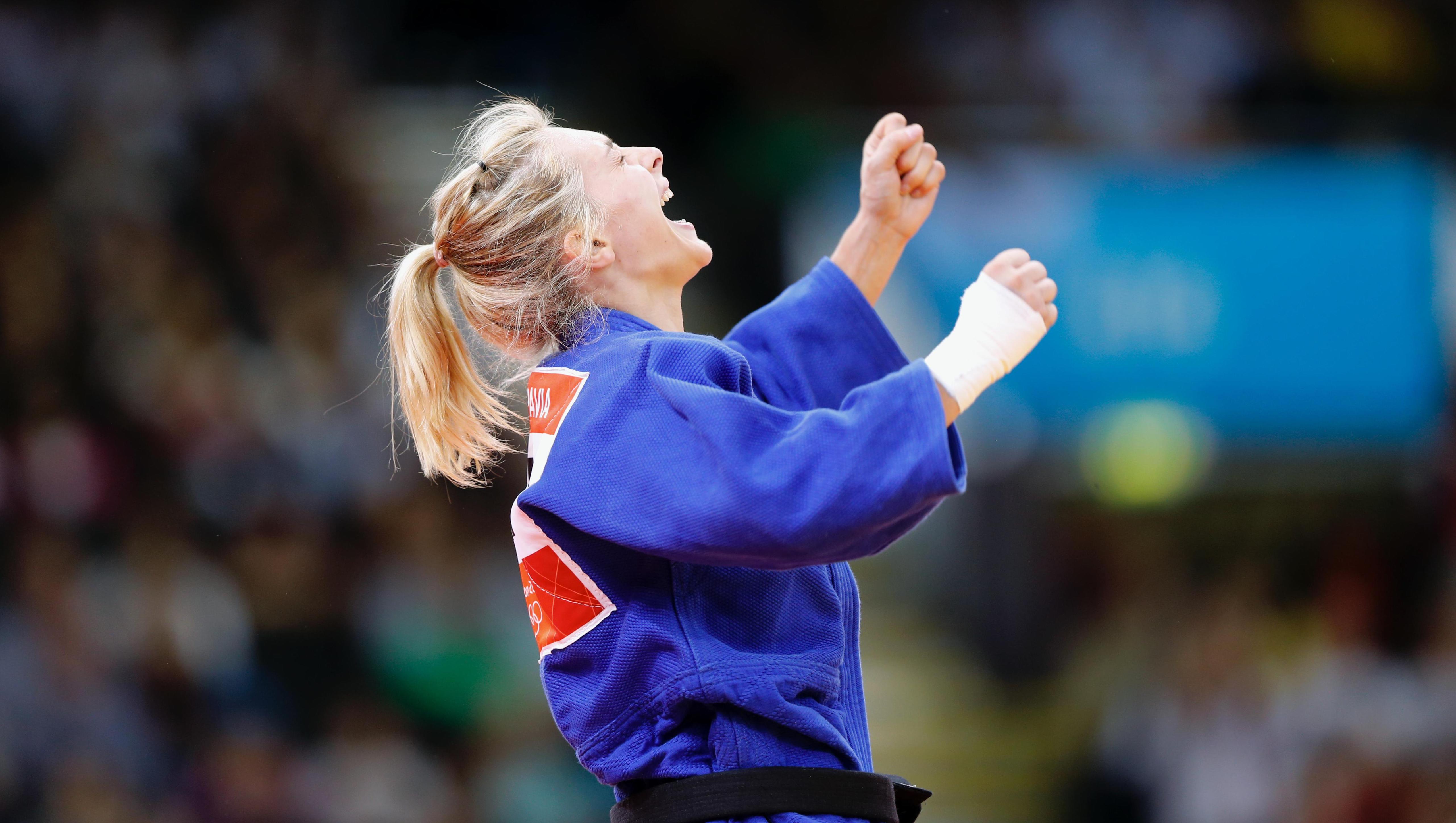 Judo athlete cheering, hands up and a little bit out to the sides.
