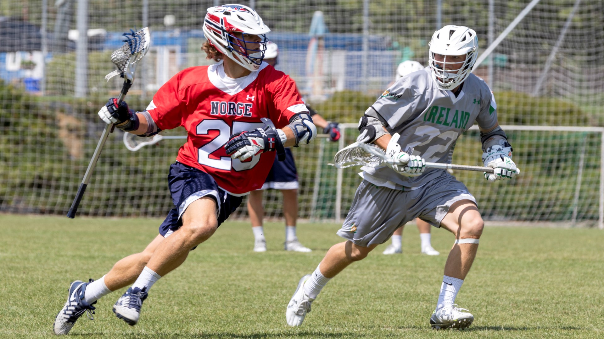 Two opponent lacrosse players running next to each other on the field.