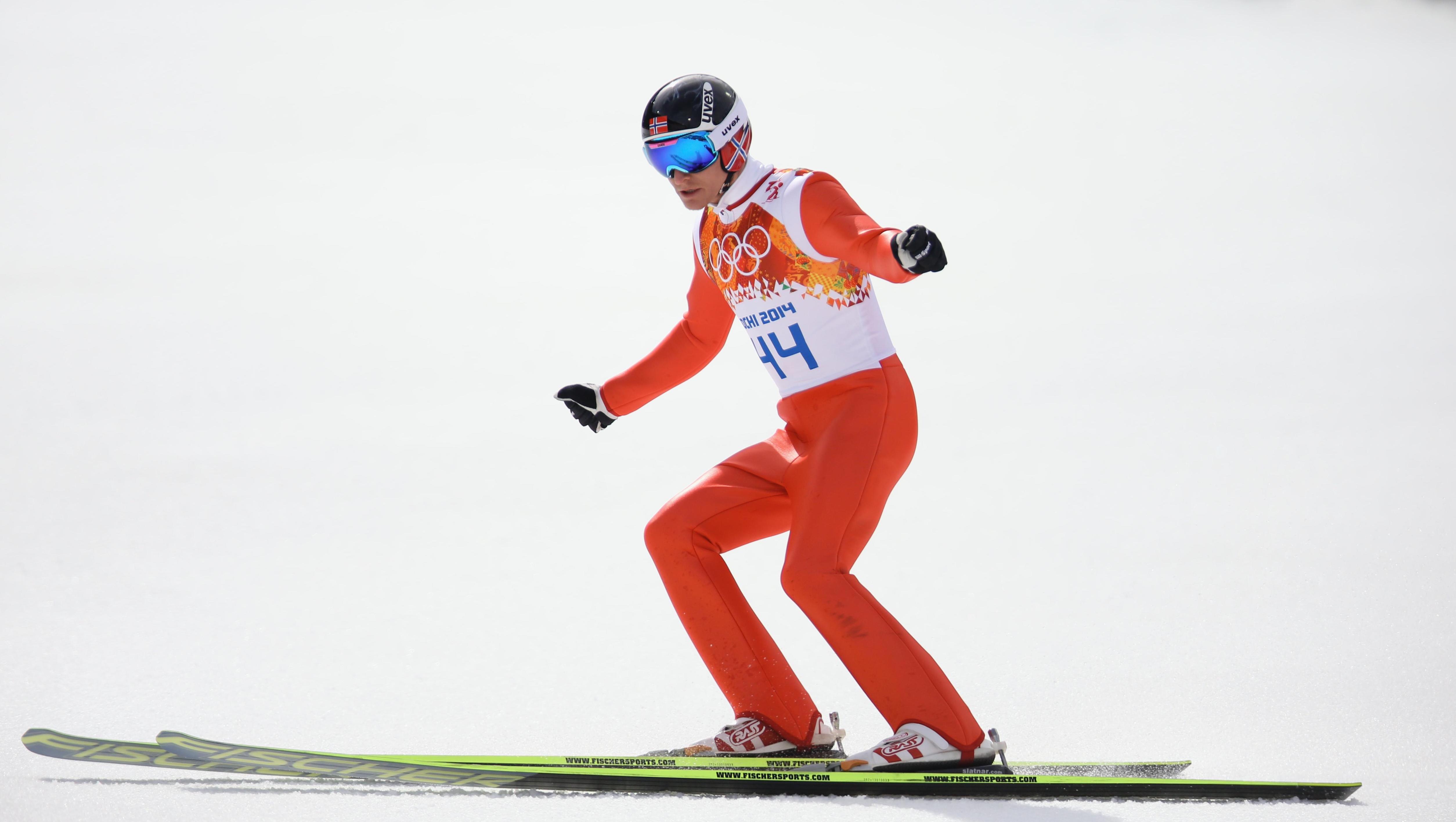 Ski jumpers on the ground about to break with the skies after a jump.