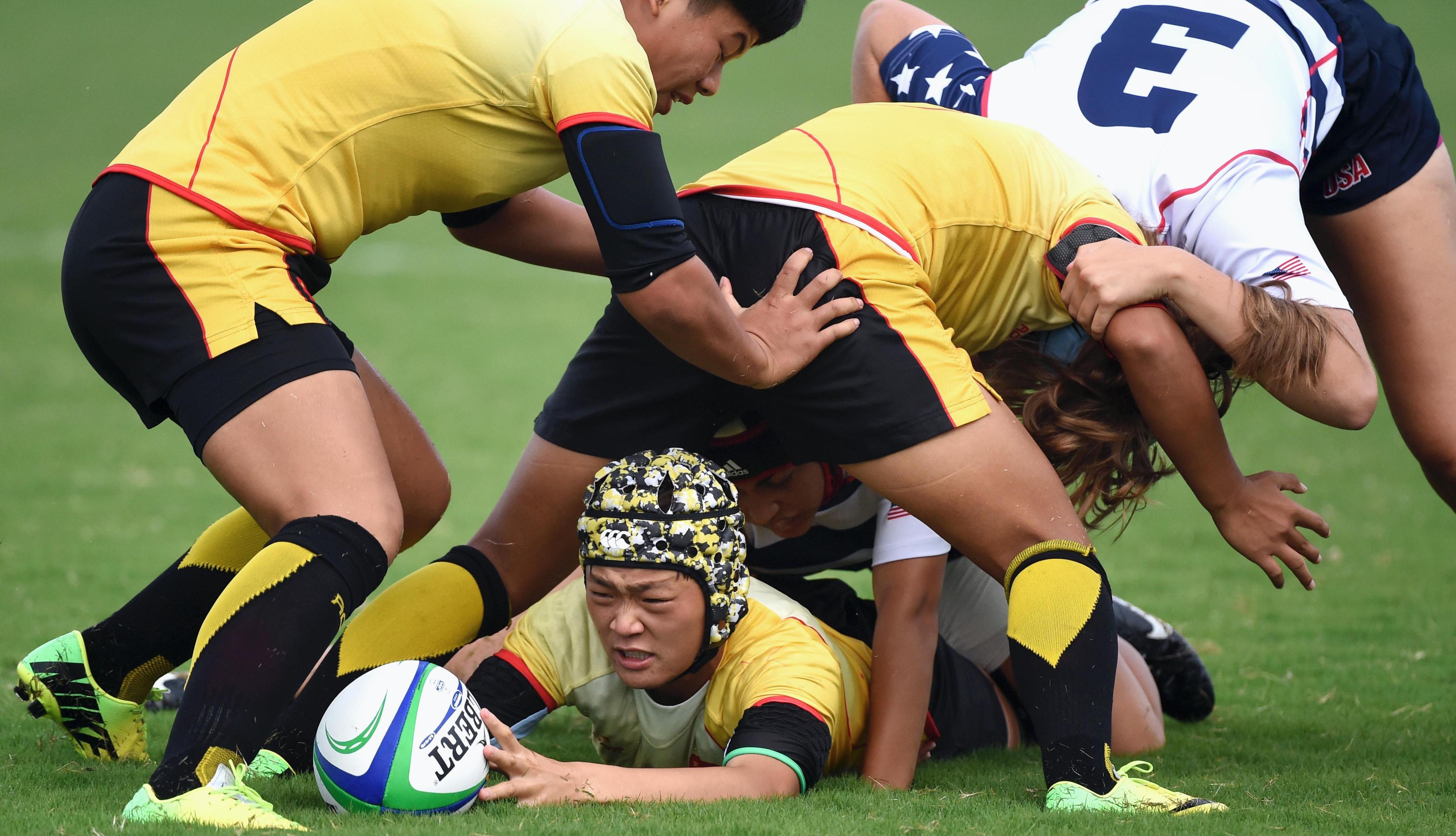 Several players in a match. One players lyes on the ground on his stomach with the ball. The others are fighting on top or over him.
