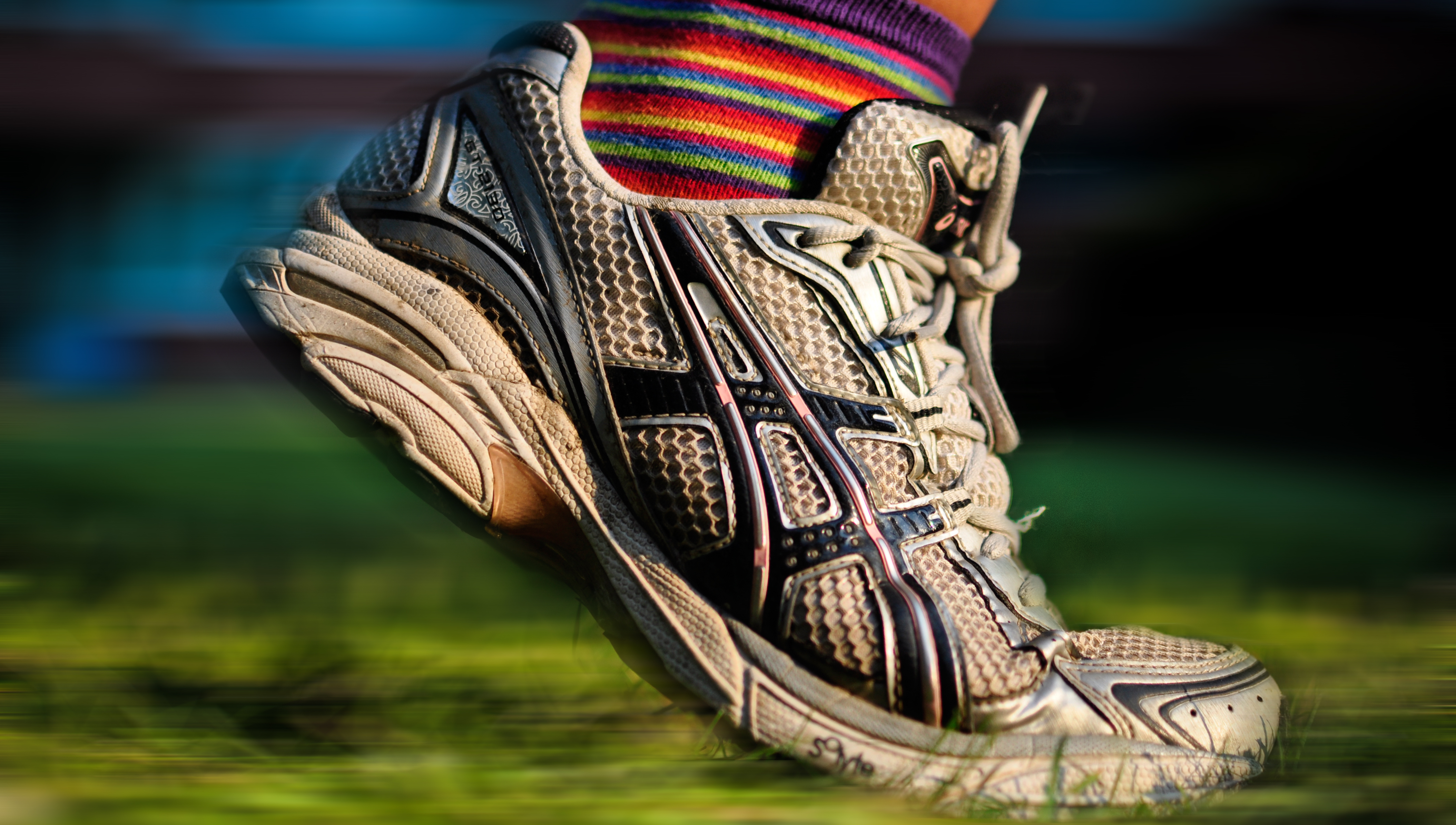 Close up of running shoe on an athlete. White and a bit dirty, moving forward.