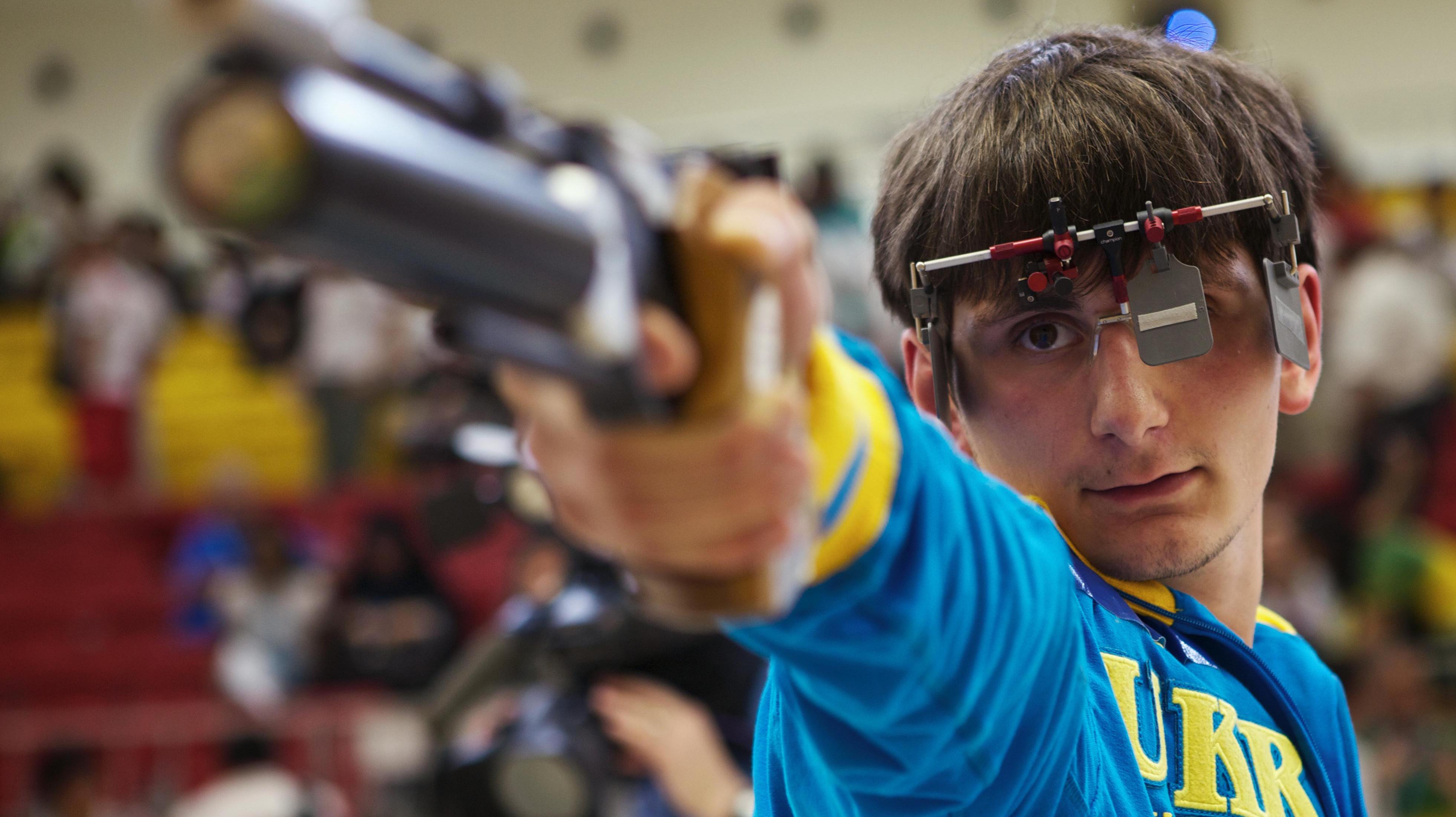 Close-up of a shooter and his gun, seen from the front, aiming.