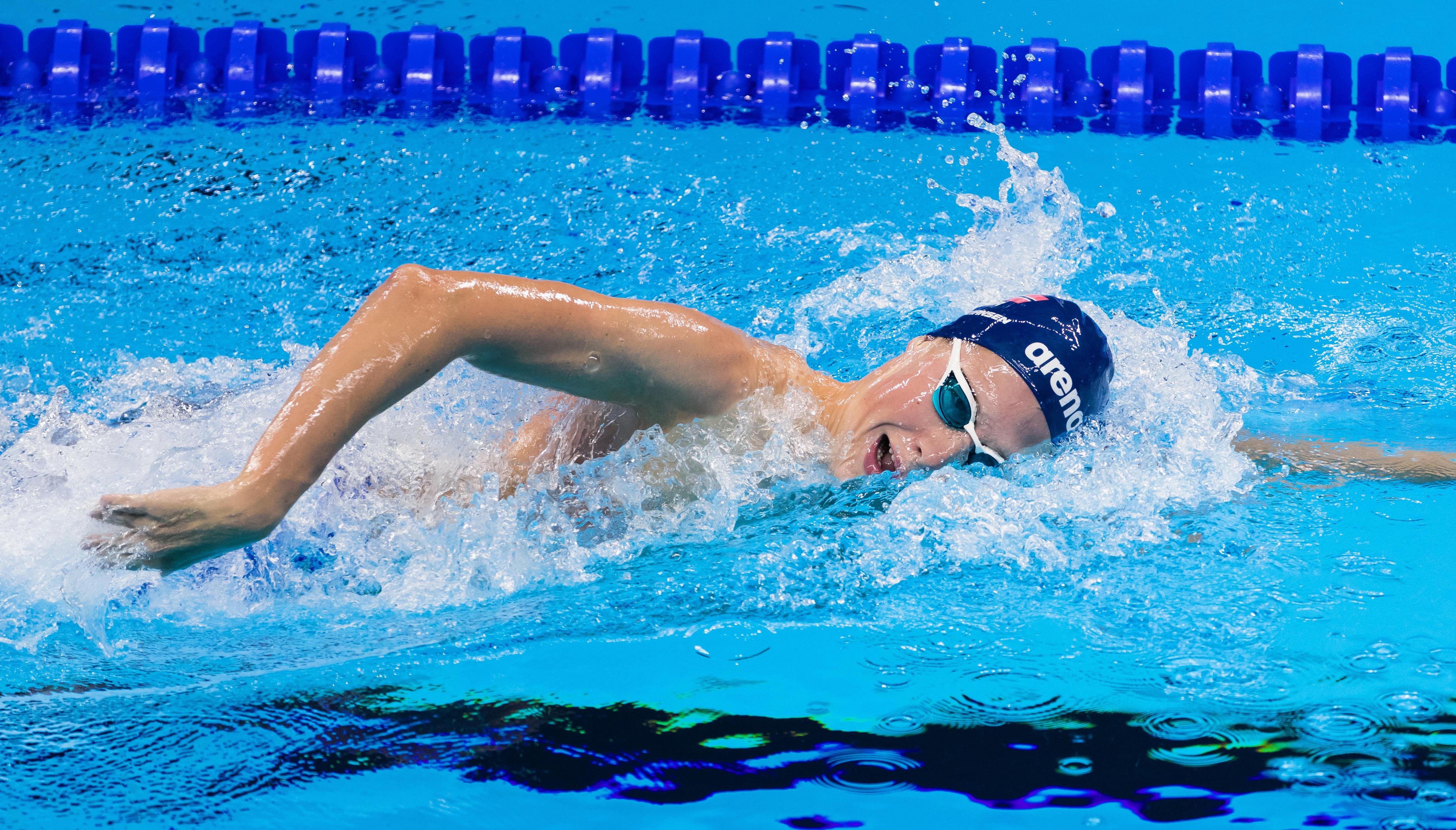 Athlete in the swimming-pool, face halfway above the water on the side.
