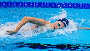 Athlete in the swimming-pool, face halfway above the water on the side.