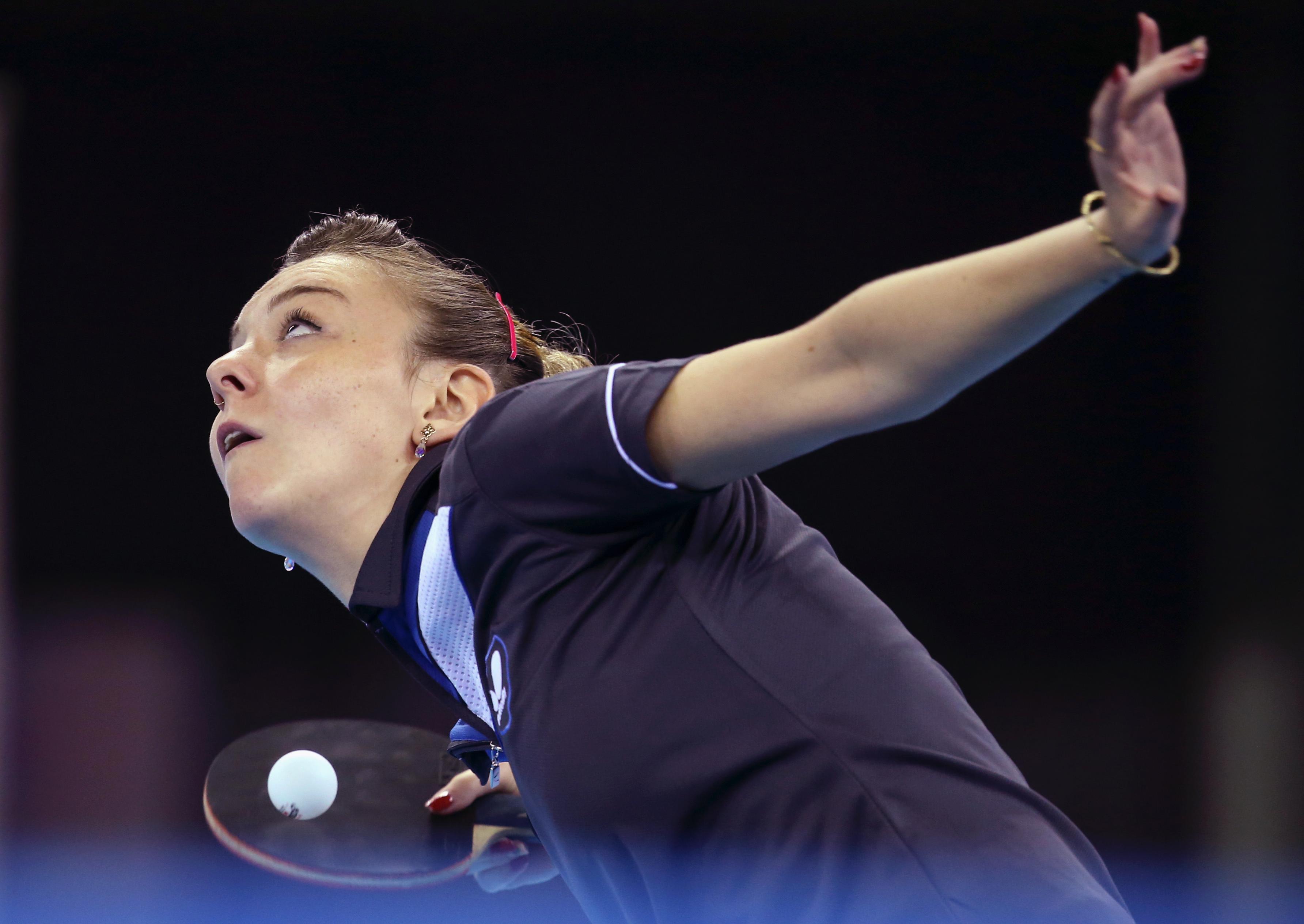 Close up of athlete about to serve the ball. Racket in her right hand, the ball is on the racket. Athlete looking up with her eyes, left hand straight forward.