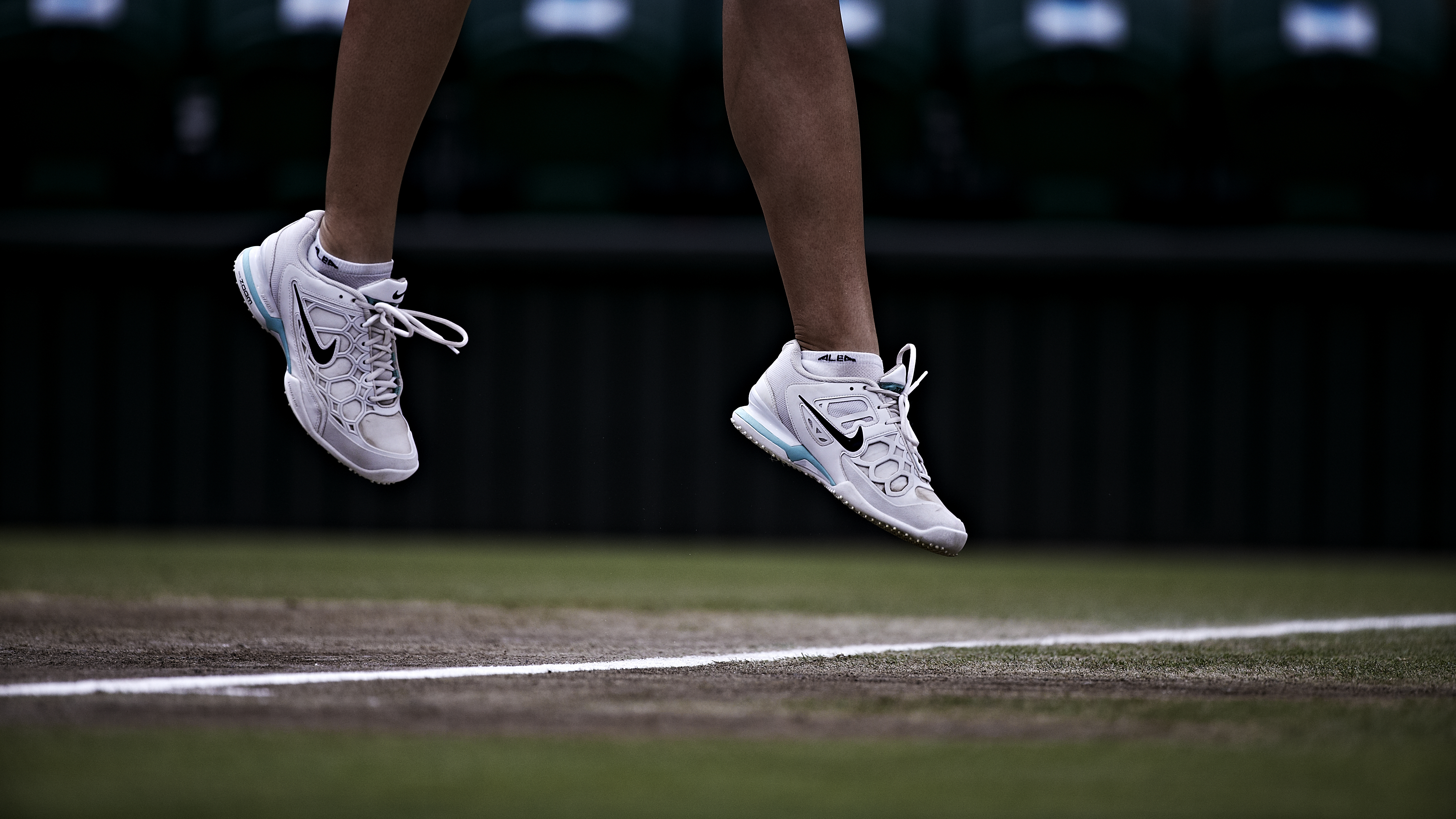 Legs and feet of an athlete in the air, up from the gras court.