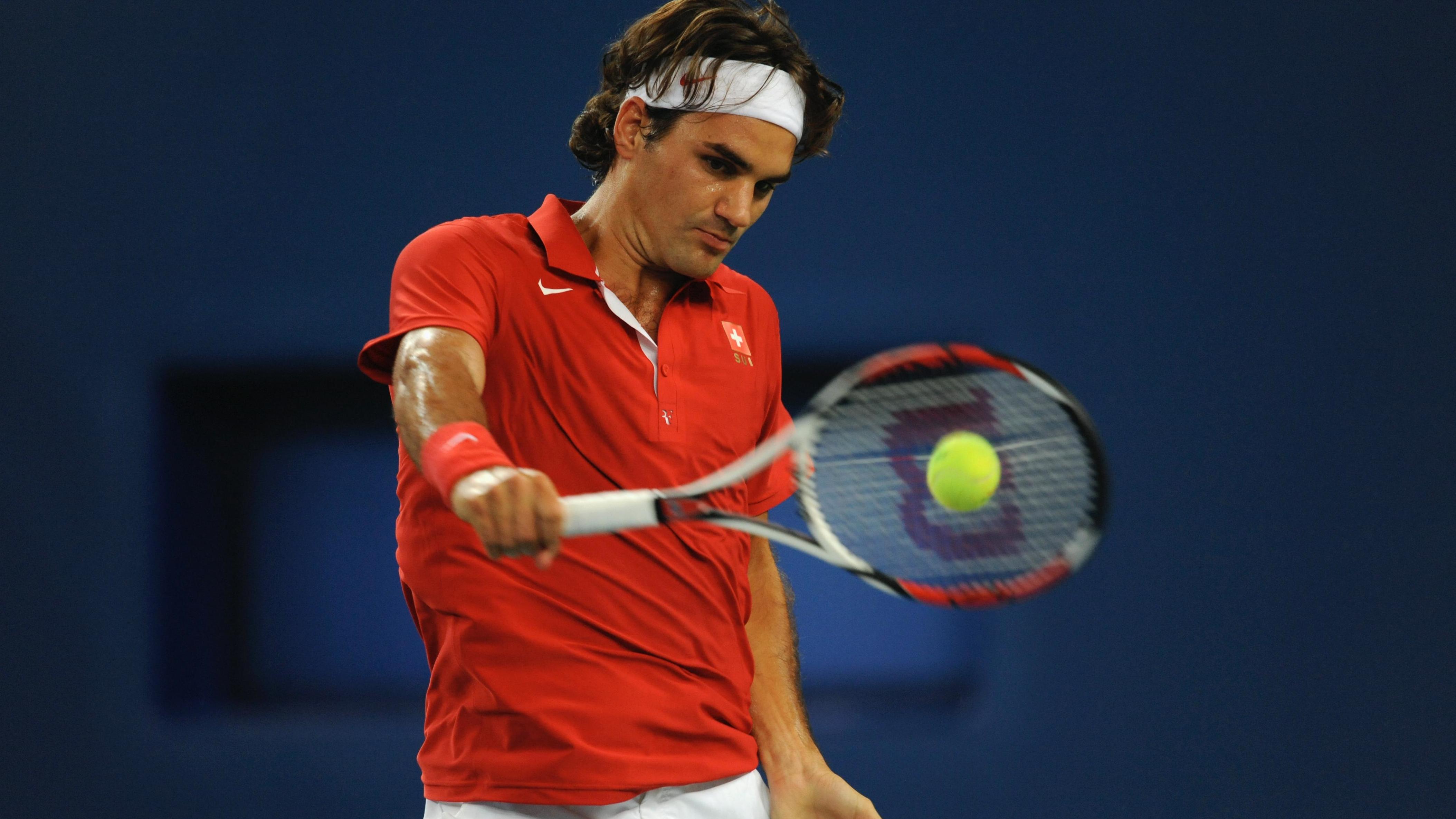 Tennisplayer Roger Federes casually hitting the tennisball with his racket, holding it in his right hand.