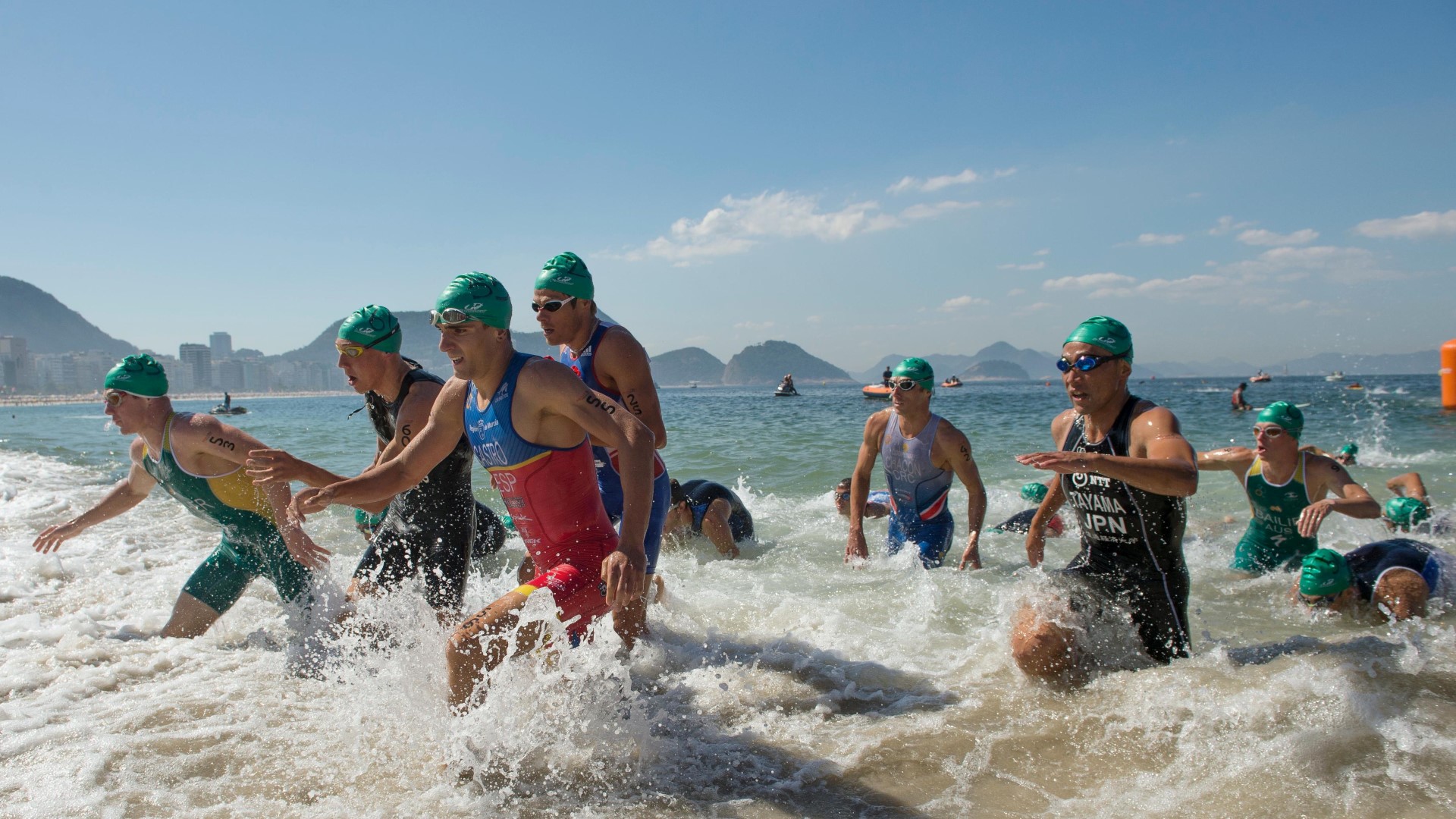 Several athletes running in the water after finishing a swim in the sea, during an Olympic competition.