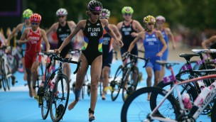 Several triathlon athletes in a race running while holding onto their bikes.