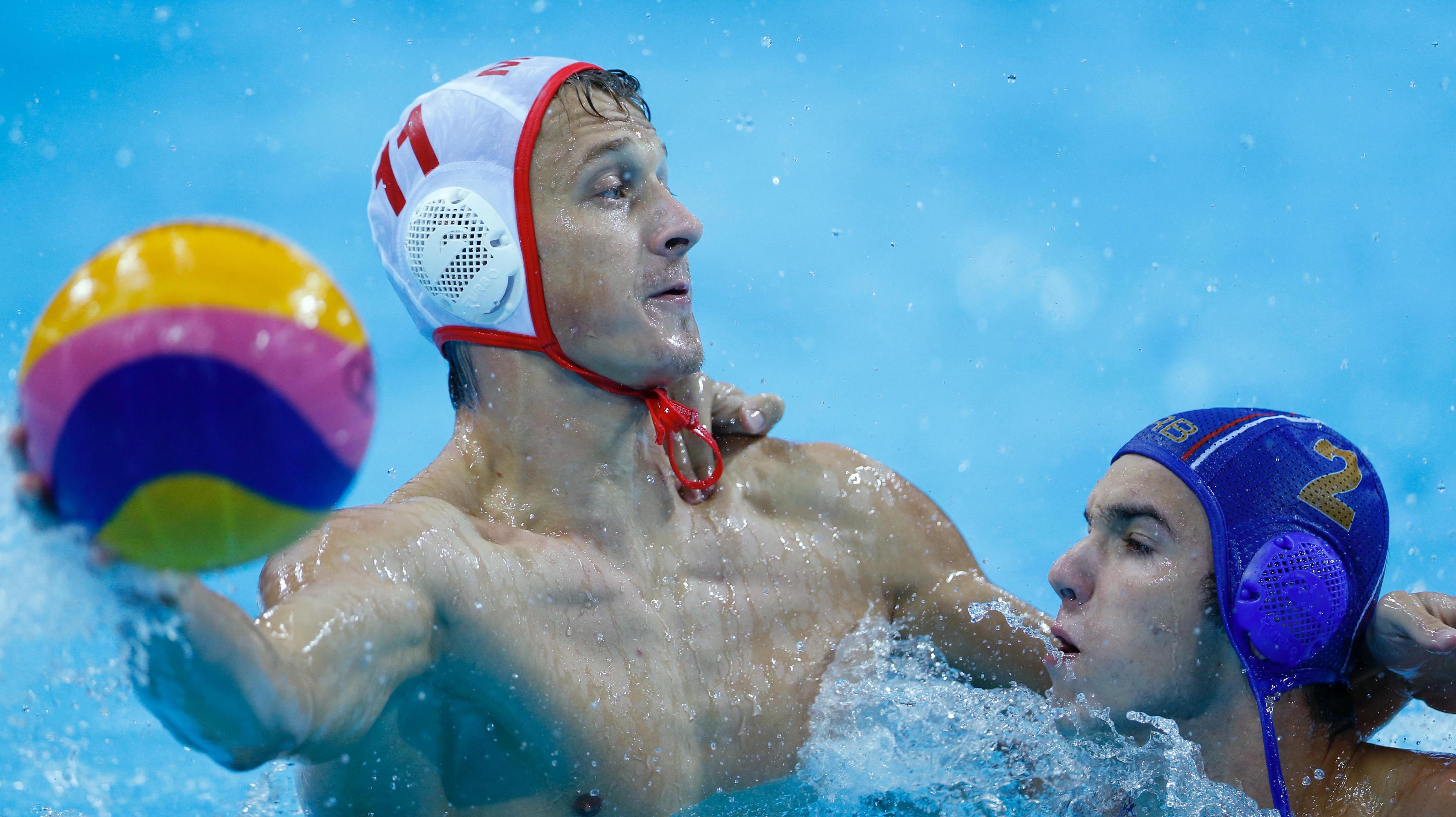 Close-up of an athlete in the pool, holding the ball in his right hand, looking forward. Water all around.